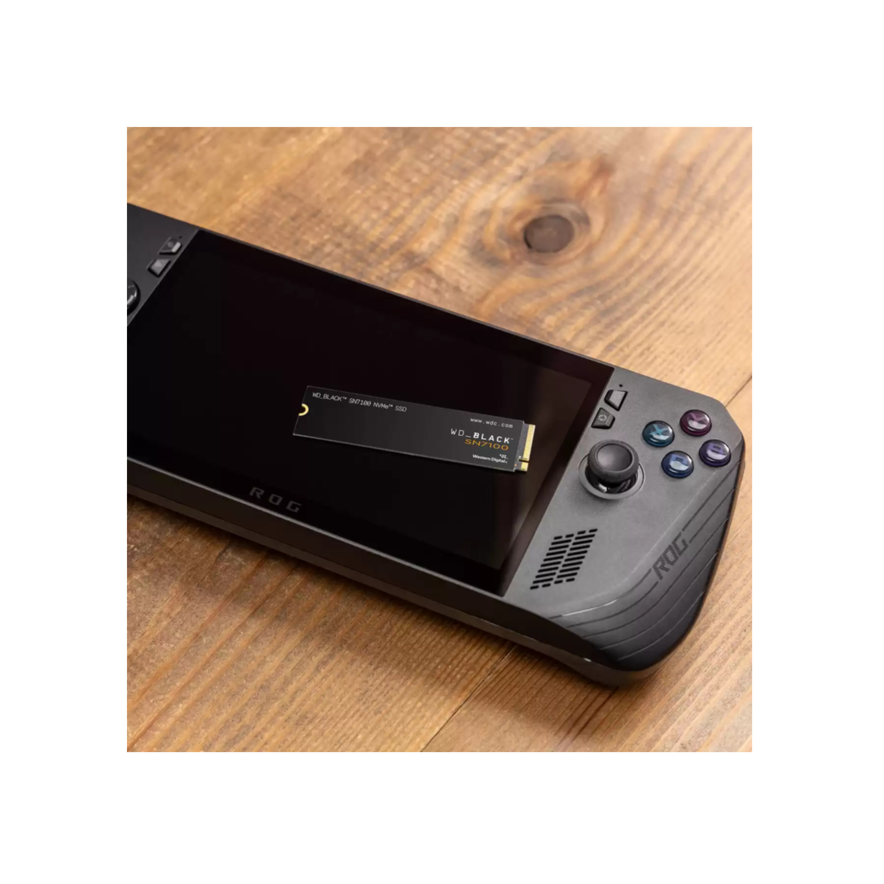 WD_BLACK SN740 SSD na przenośnym urządzeniu do gier, na drewnianej powierzchni. Urządzenie jest czarne.