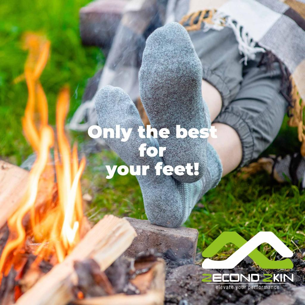 Füße in grauen Socken in der Nähe eines Lagerfeuers mit Text: Nur das Beste für Ihre Füße! ZECONDKIN-Logo.