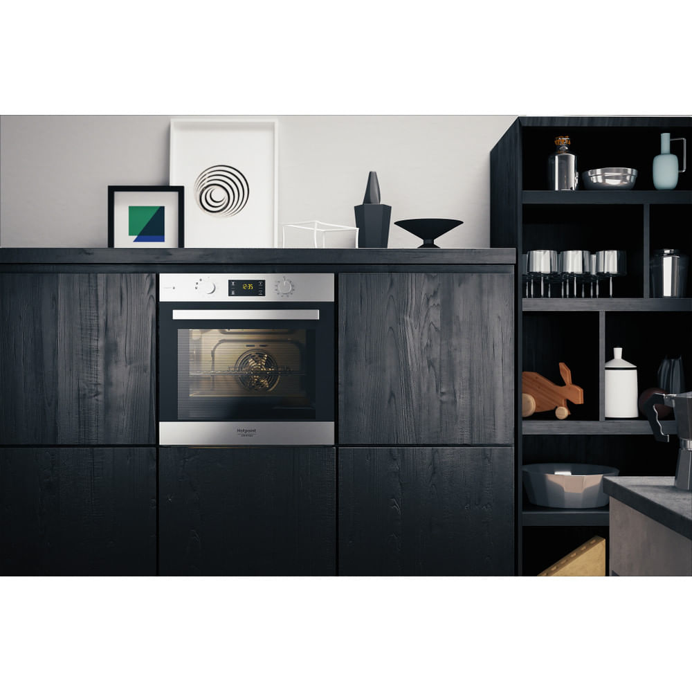 Un forno in cucina, con opere d'arte e decorazioni, incassato in mobili in legno scuro.