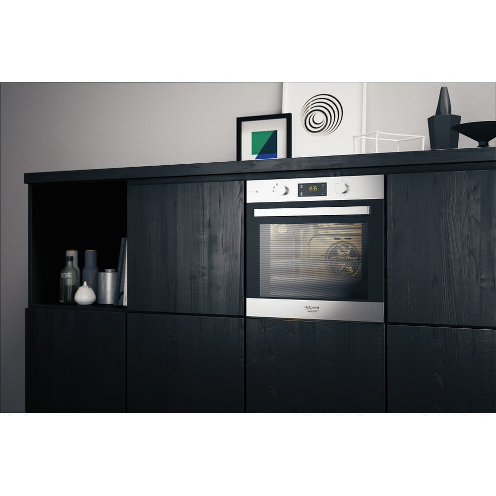 Un forno in un ambiente cucina, con opere d'arte e decorazioni, integrato in mobili in legno scuro.