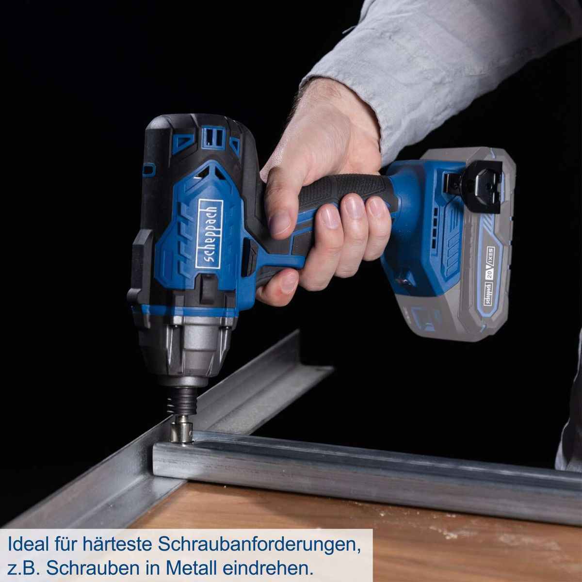 Osoba używa niebiesko-czarnego wkrętaka udarowego na metalowej ramie. Narzędzie jest zasilane baterią.