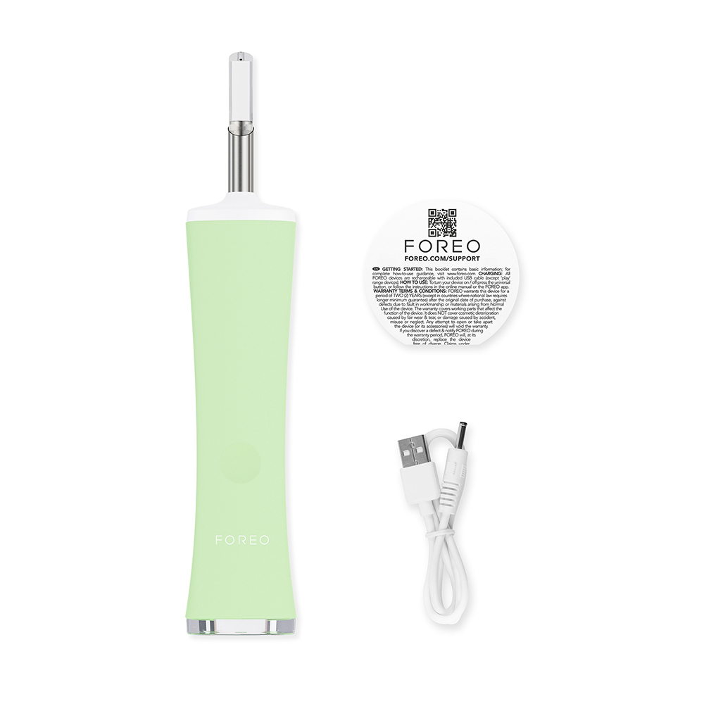 A green Foreo device with a white USB cable, a support card, and a white background.