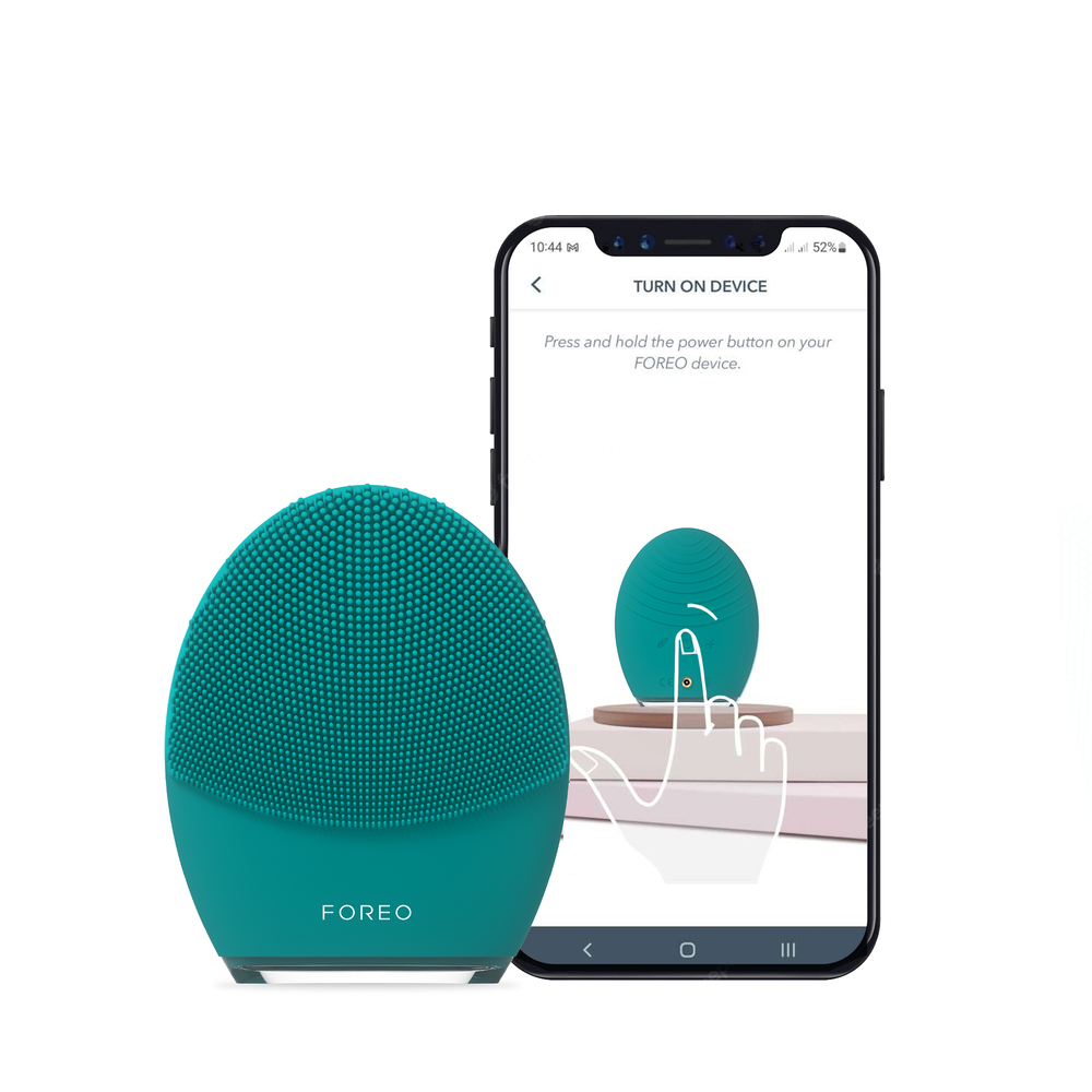 Een teal Foreo-apparaat naast een smartphonescherm met instructies om het aan te zetten.
