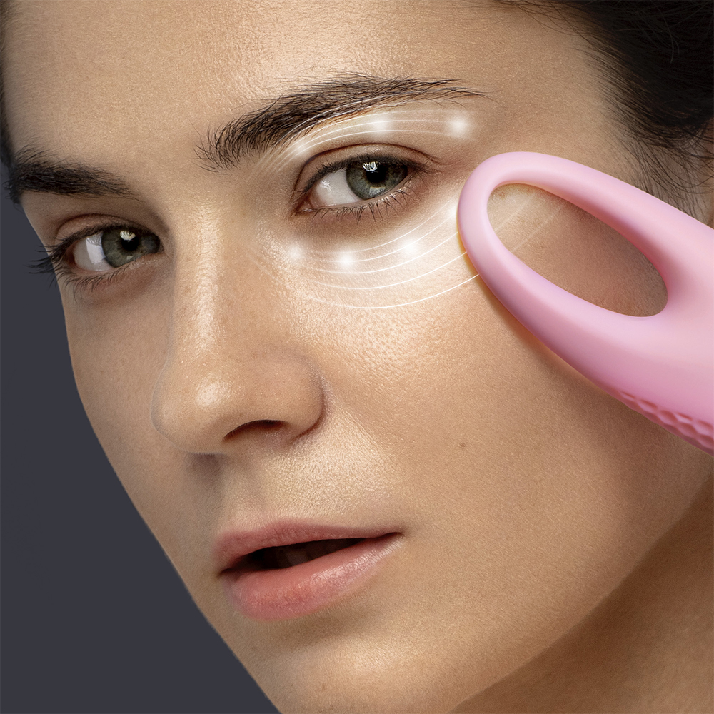 Vrouw gebruikt roze gezichtsmassager. Witte lijnen benadrukken ogen. Donkere achtergrond.