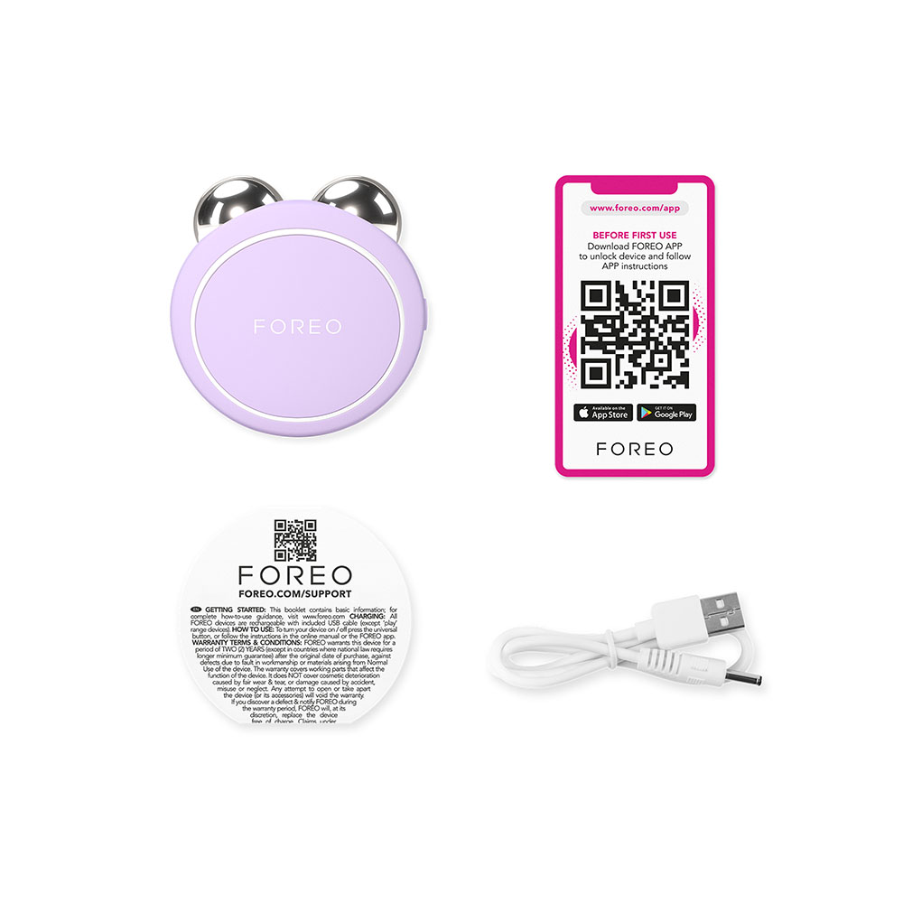 Un appareil Foreo, des instructions et un câble de chargement. L'appareil est un objet violet en forme d'ours.