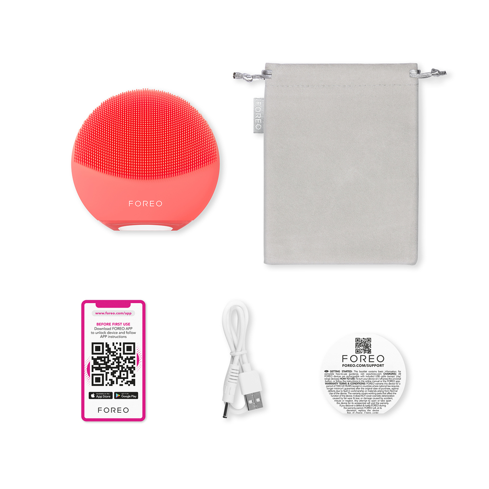 Red Foreo device, charging cable, and accessories on a white surface.