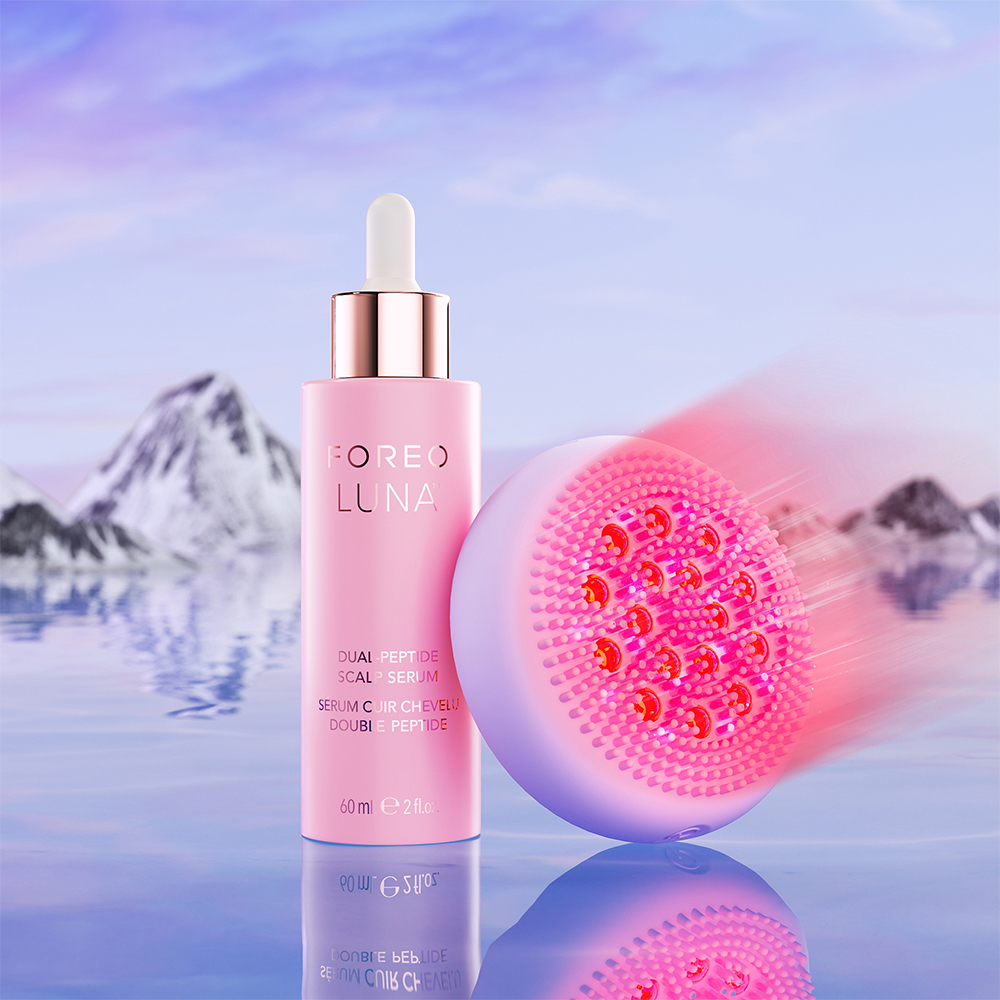 Foreo Luna-apparaat en serumfles, met een schilderachtige achtergrond van water en bergen.