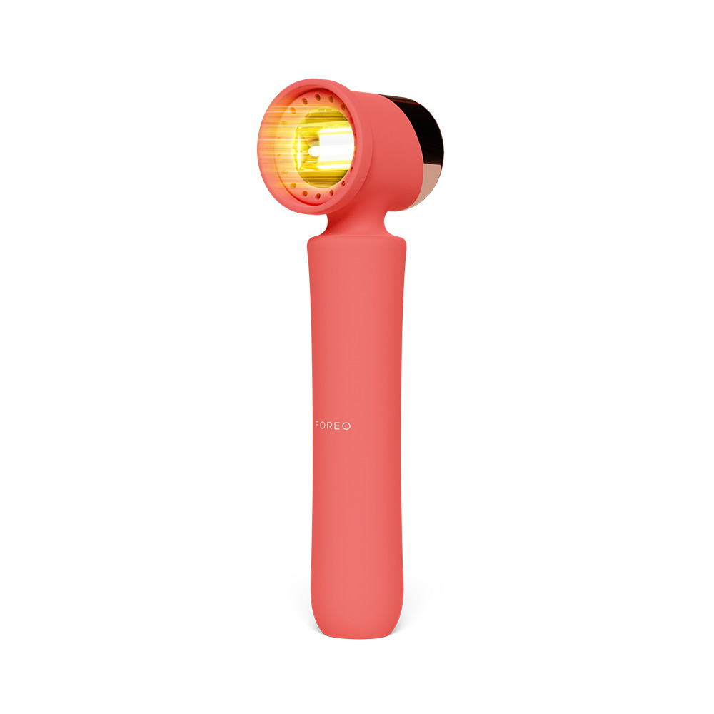 Coral FOREO device with a gold face, handle design, and a white background.