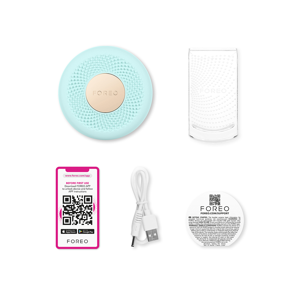 FOREO cihazı, şarj standı ve aksesuarlar. Mavi bir cihaz, şeffaf bir stand, bir QR kod kartı ve bir USB kablosu içerir.