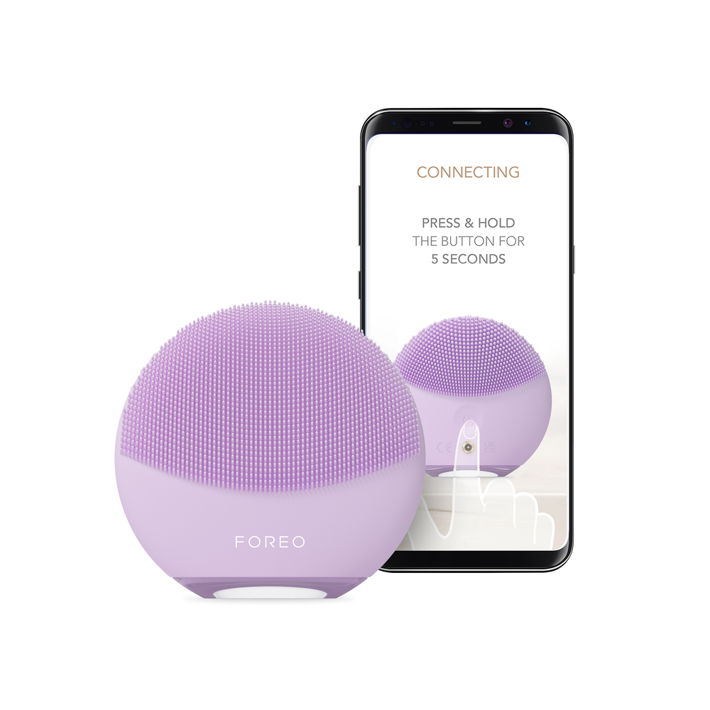 A purple FOREO face brush and a smartphone displaying the device and instructions for use. White background.