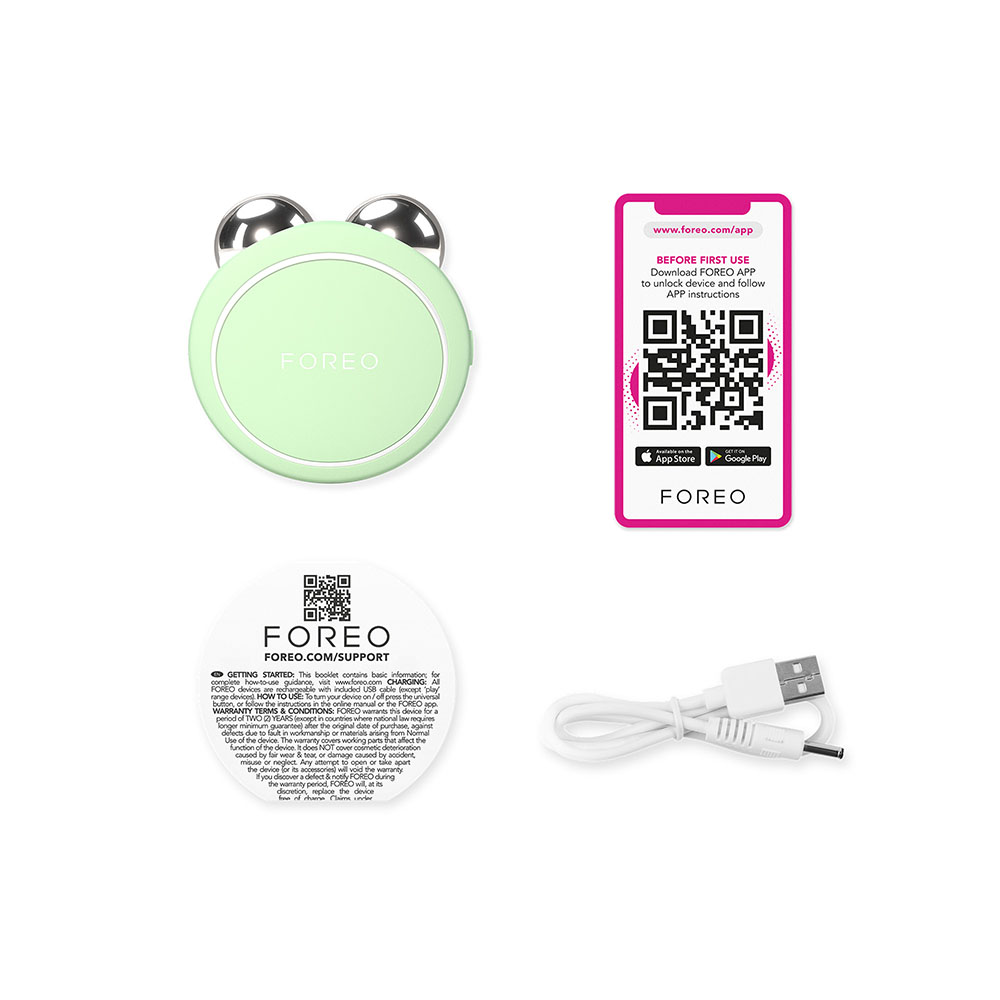 A Foreo Bear device, instructions, a charging cable and a phone with a QR code on a white surface.
