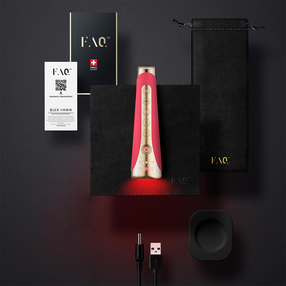 Rood en goud schoonheidstoestel met accessoires op zwart oppervlak. Oplaadkabel en zwarte standaard zichtbaar.