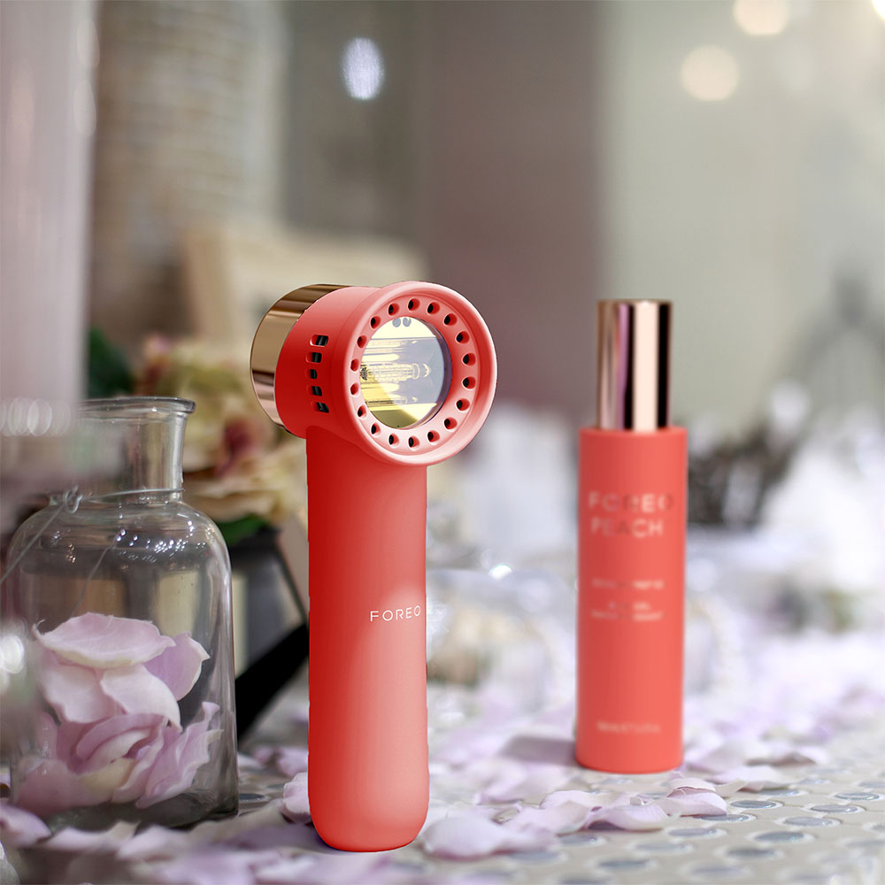 Red beauty device and bottle with a blurred background of flowers and a vase.