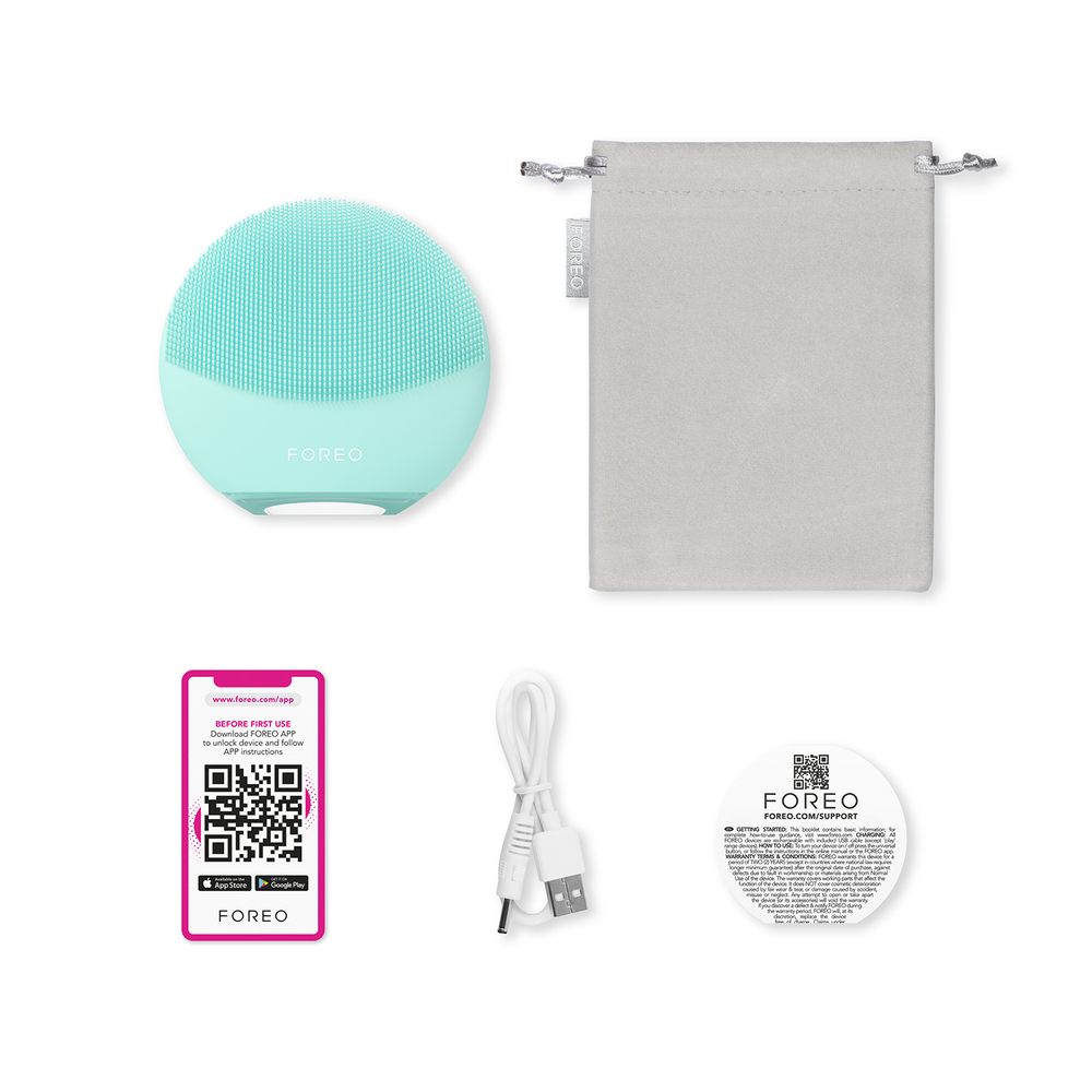 A set of skincare items, including a facial cleansing device, a case, a charging cable, and instructions.