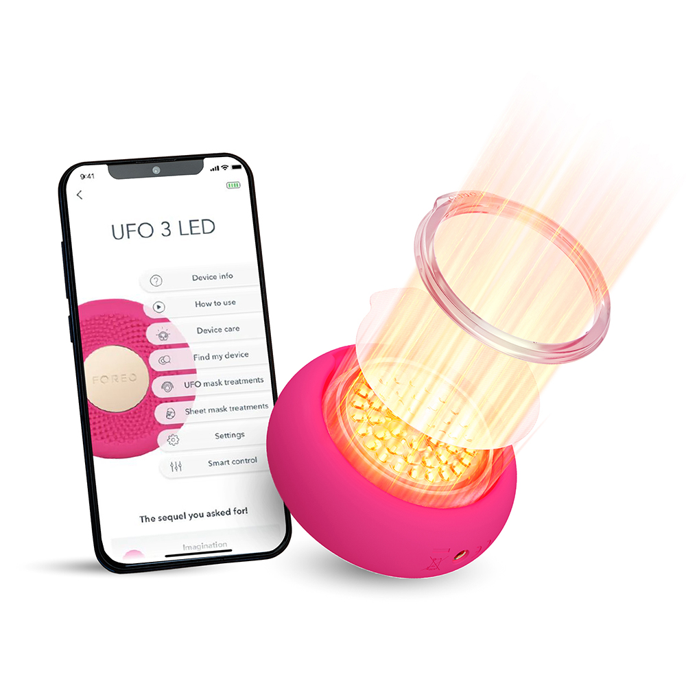 Pink Foreo device and phone with app interface. Light shines from the device. White background.