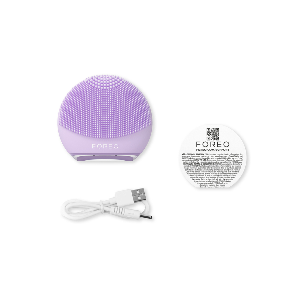 Foreo device, instructions, and charging cable on a white surface. The device is round and purple.