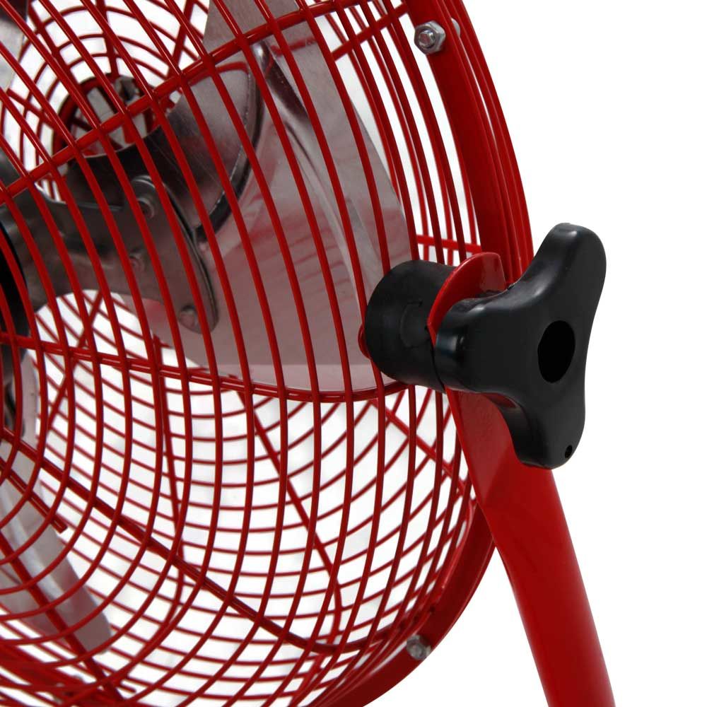Primer plano de la jaula de un ventilador de metal rojo, mostrando las aspas y una perilla negra.