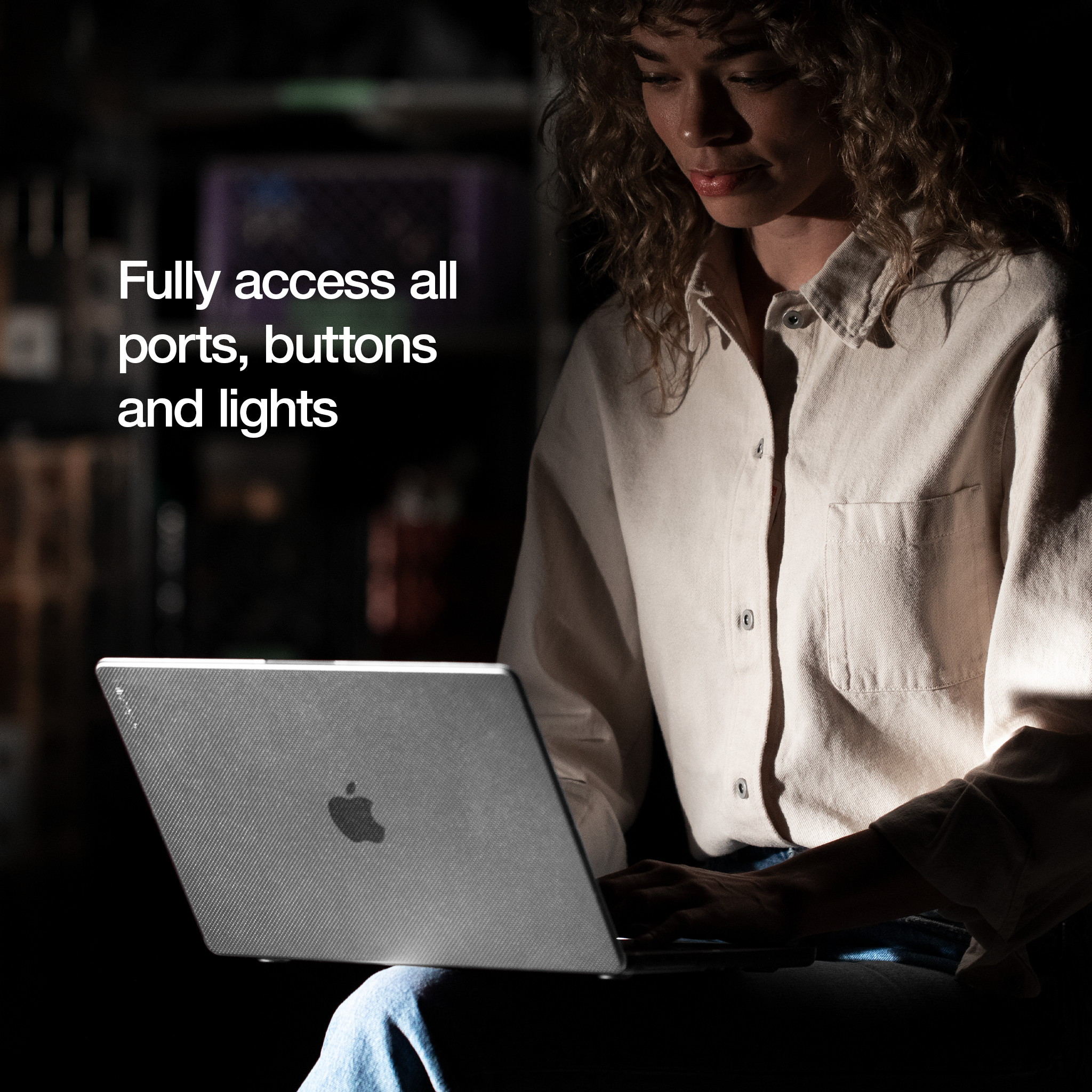 Una donna usa un laptop con una custodia grigia. Il laptop è in un ambiente buio.
