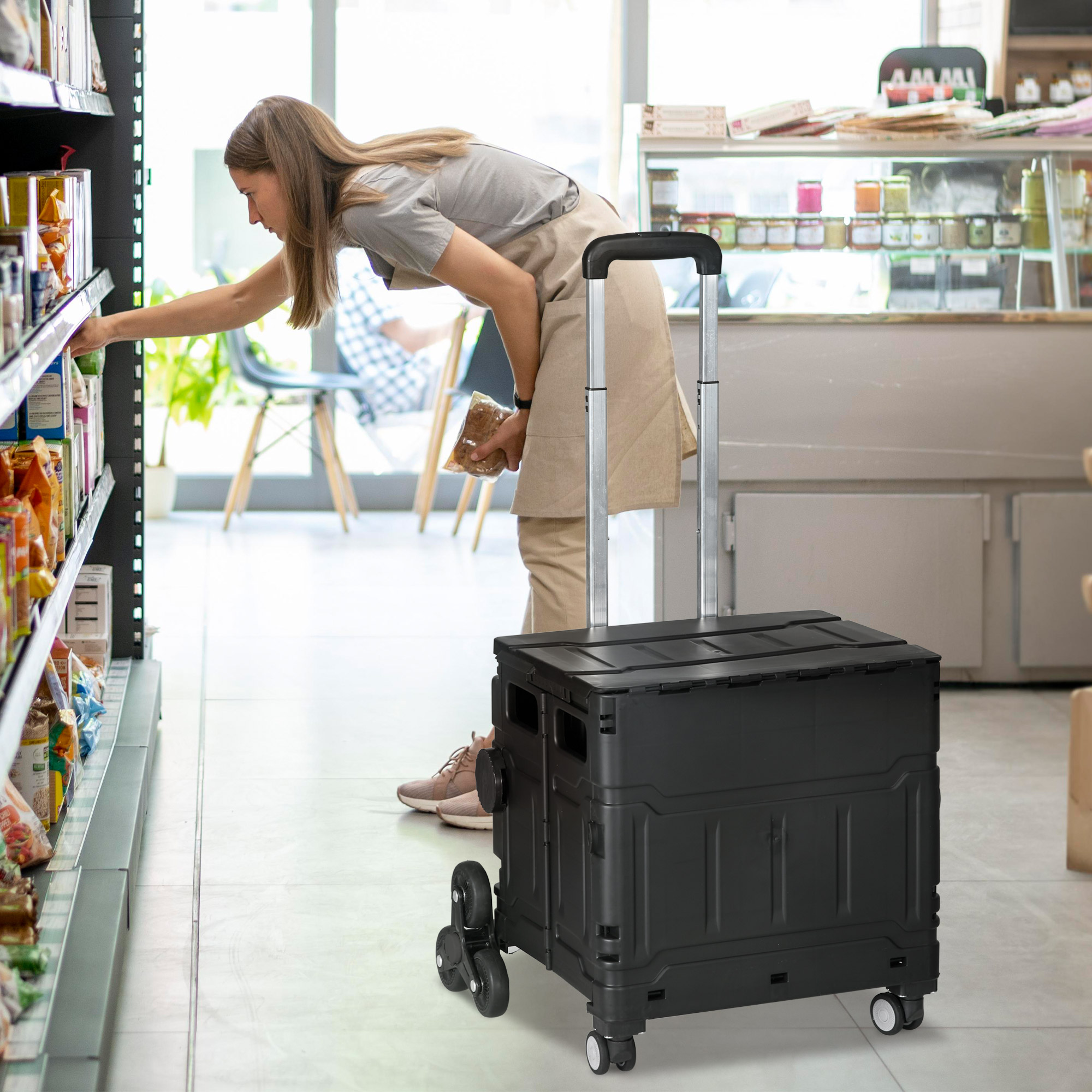 Frau beim Einkaufen in einem Lebensmittelgeschäft mit einem schwarzen Einkaufswagen.