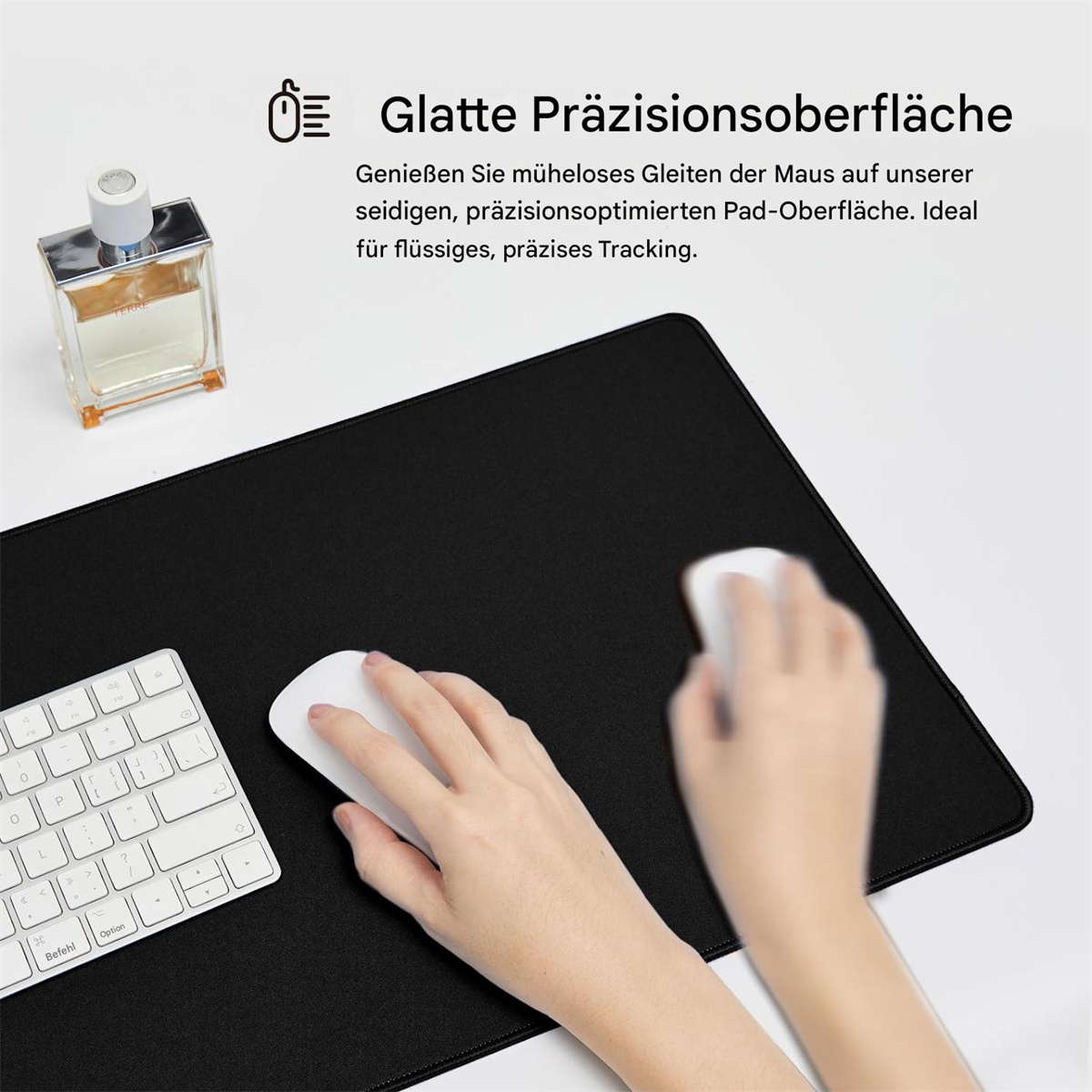 Eine schwarze Maus auf einem schwarzen Mauspad mit einer weißen Tastatur. Oben links befindet sich eine Parfümflasche.