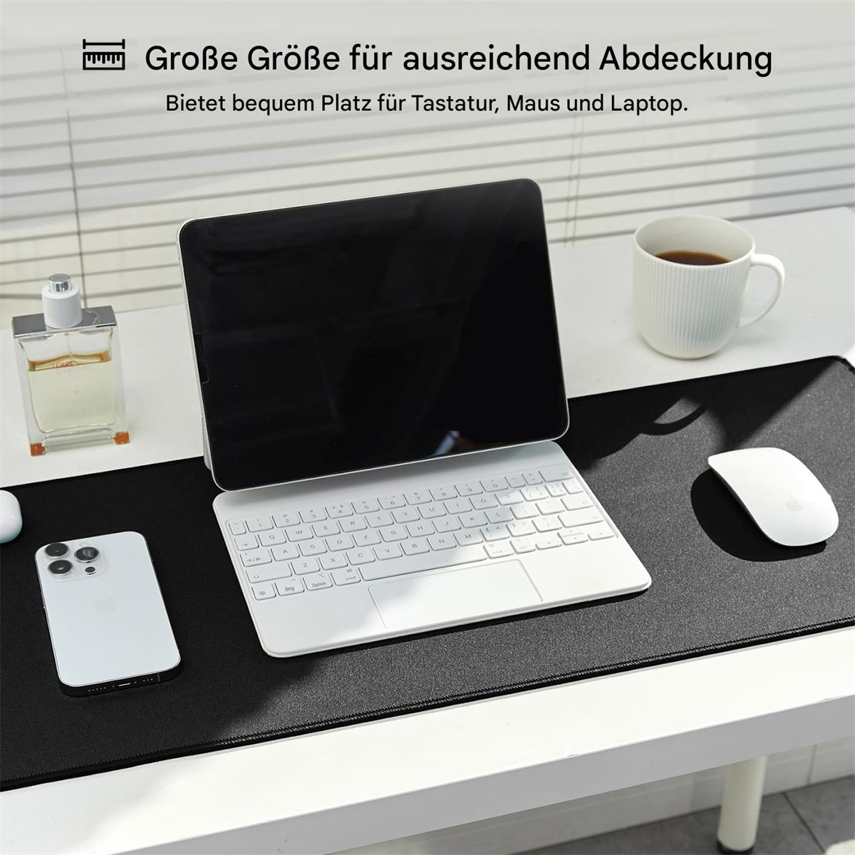 Schwarze Schreibtischunterlage mit Tastatur, Maus, Tablet und Kaffee. Weißer Hintergrund.