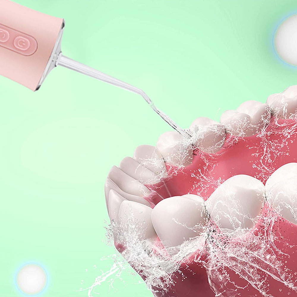 Rosa Wasser-Flosser, der Wasser auf die Zähne sprüht. Grüner Hintergrund.