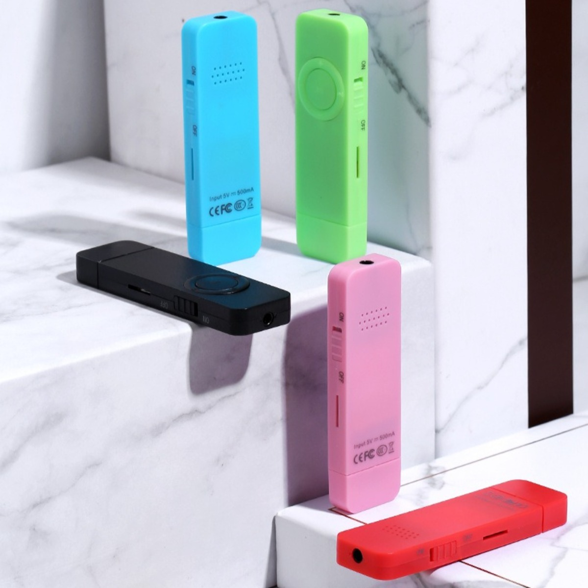 Fünf bunte Mini-USB-Ladegeräte. Blau, grün, schwarz, rosa und rot. Einige haben Knöpfe und die Wörter 'ON' und 'OFF'.