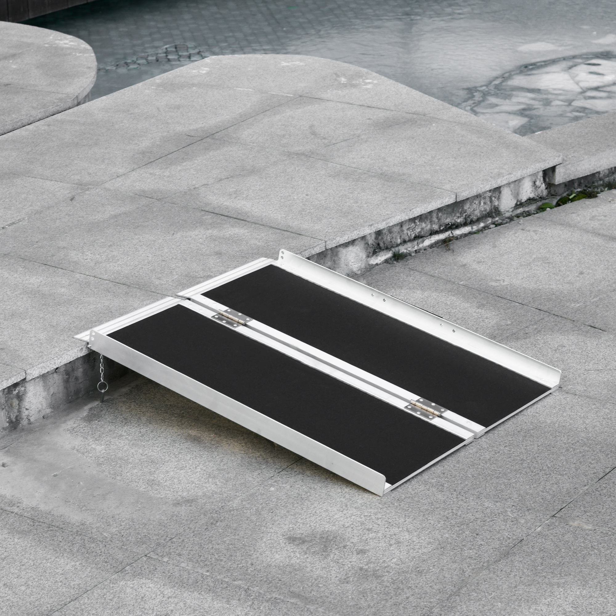 Eine silber-schwarze Rampe auf einer Betonoberfläche. Die Rampe ist zusammengeklappt und einsatzbereit.