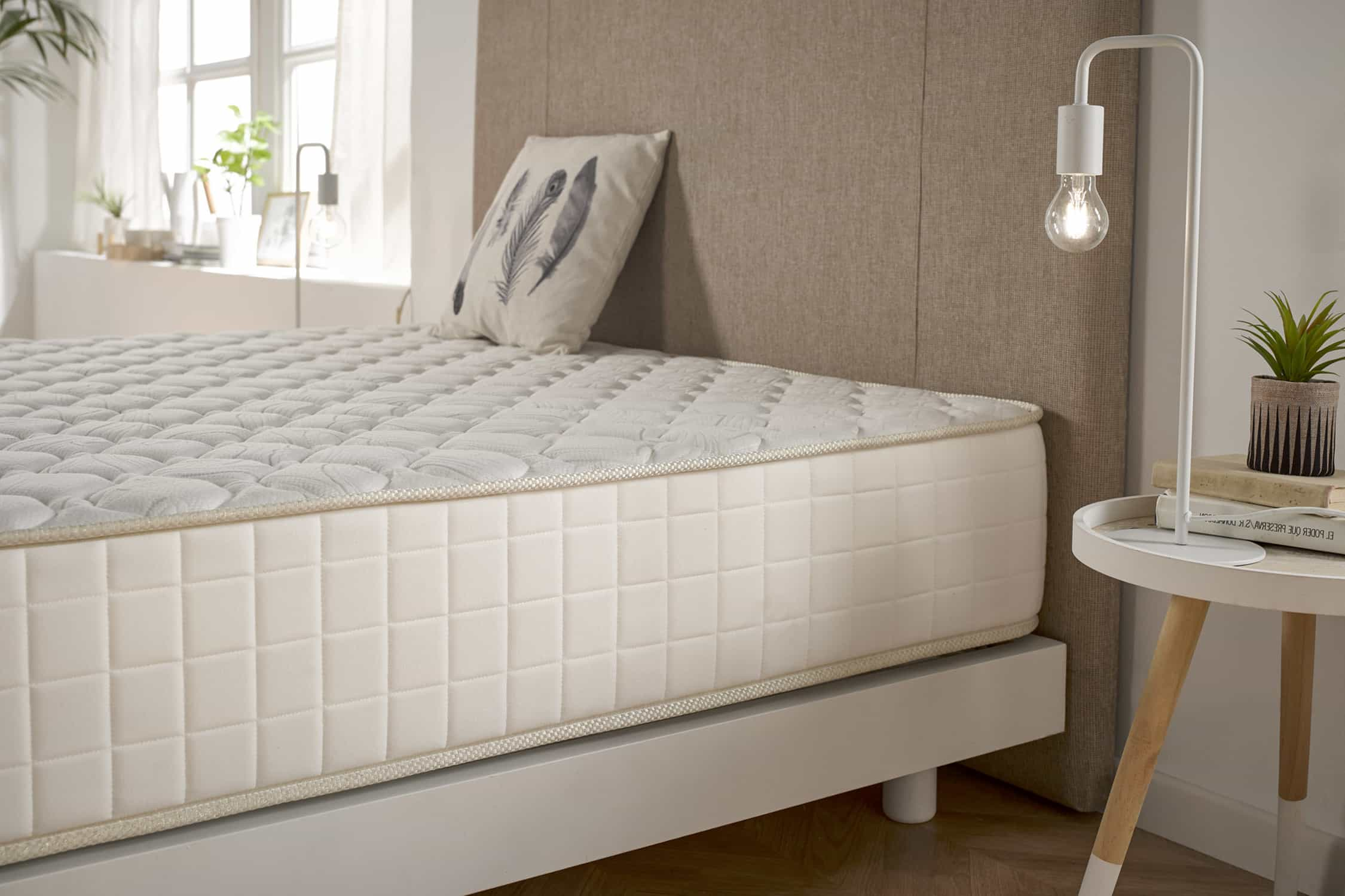 Dormitorio con cama. El colchón tiene una superficie estampada. Hay una lámpara y mesa.