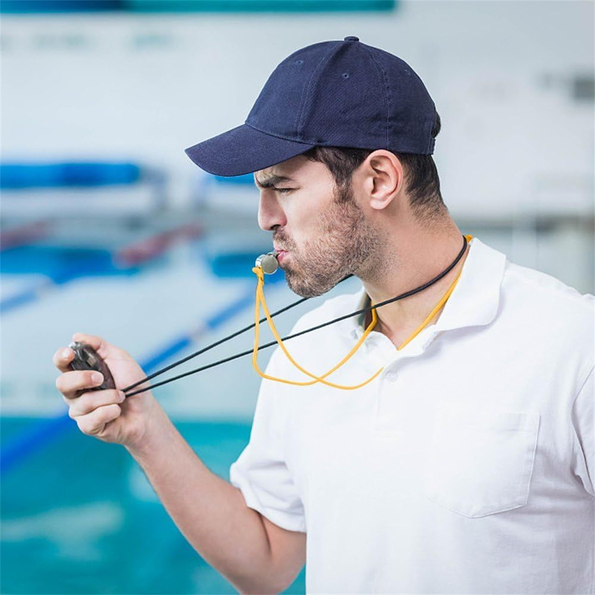 Mann mit Pfeife, Stoppuhr und Mütze am Pool. Fokus auf den Mann und seine Aktionen.