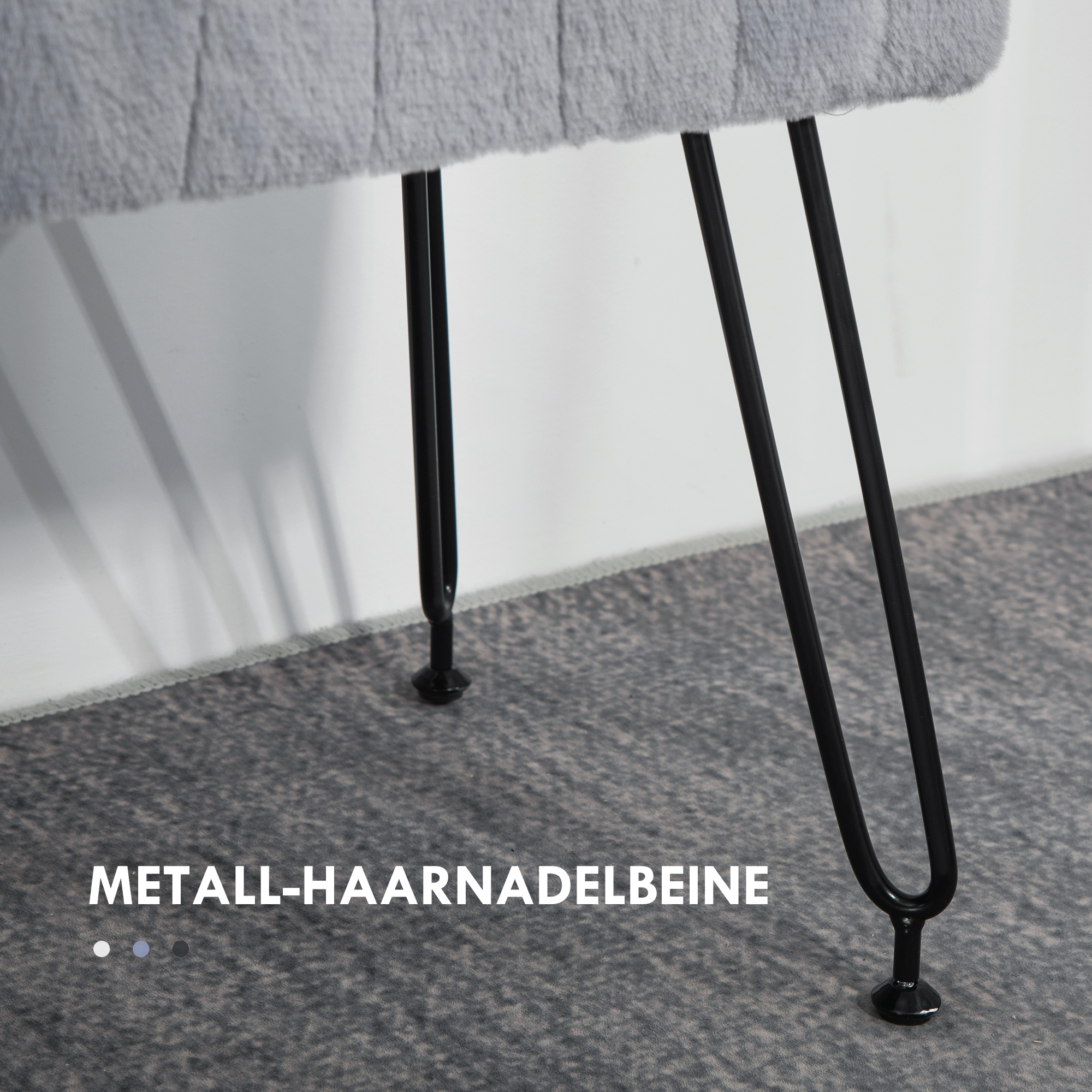 Nahaufnahme einer grauen Plüschbank mit schwarzen Haarnadelbeinen und einem grauen Teppich.