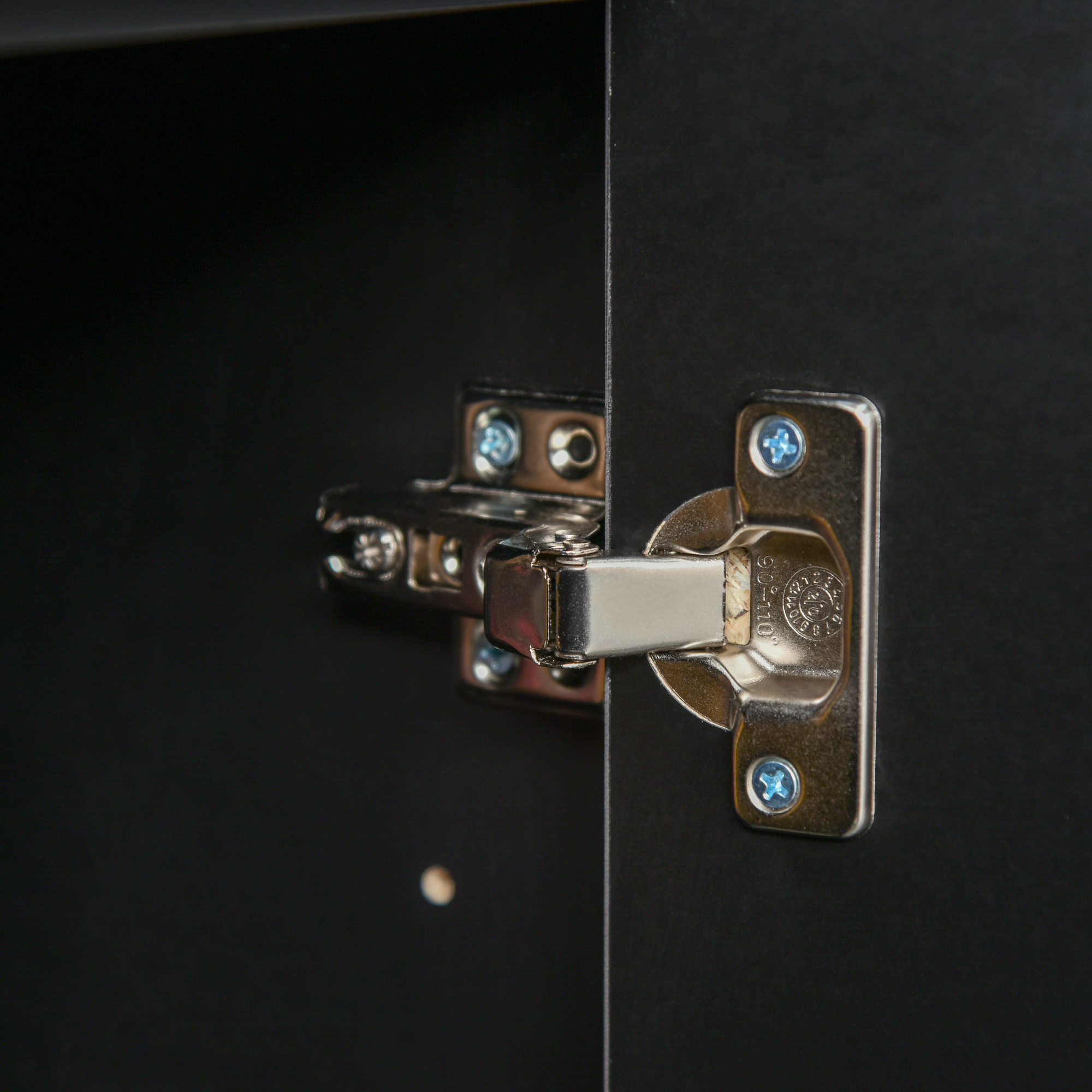 Eine Nahaufnahme eines Scharniers an einem schwarzen Schrank.