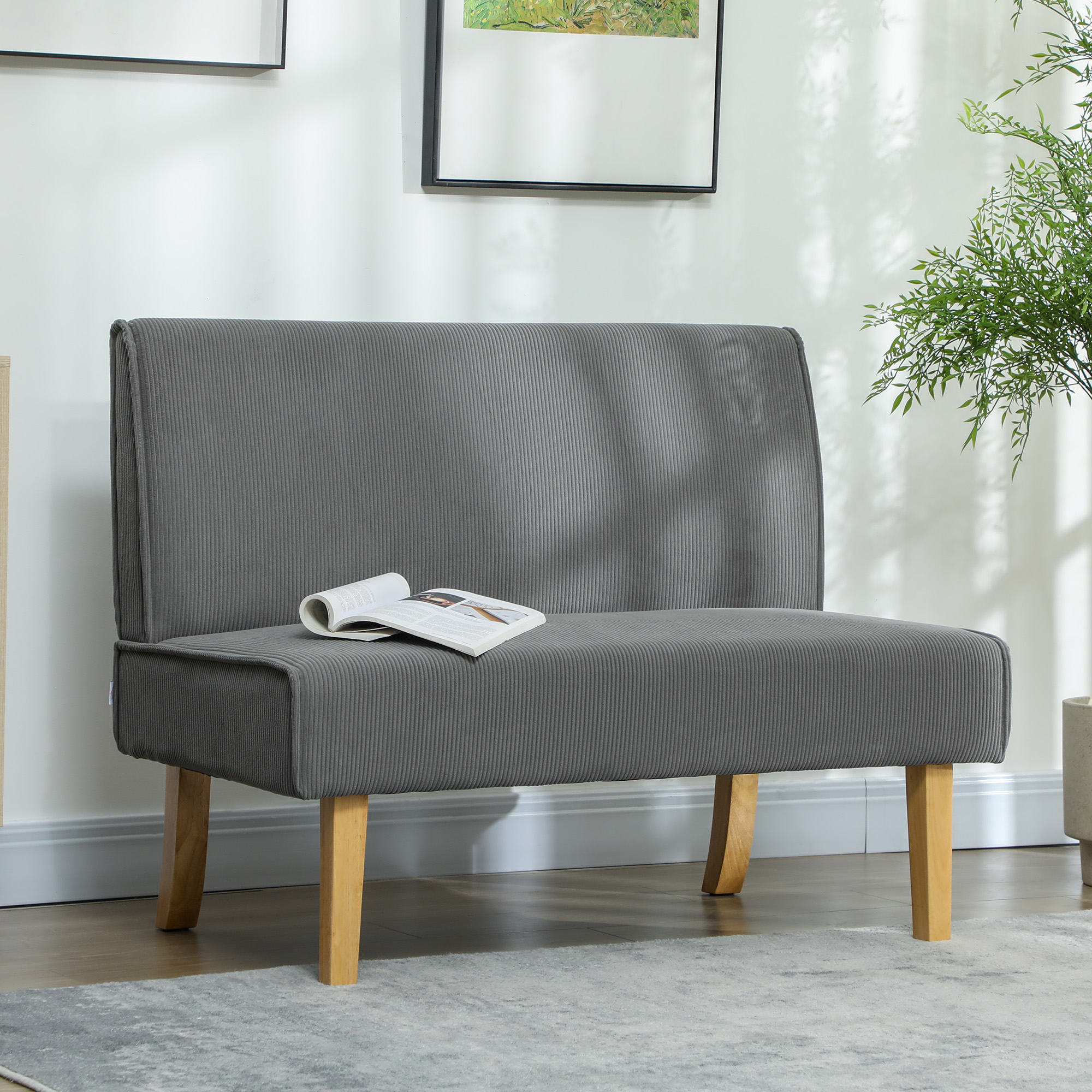 Graues Sofa mit Buch, in einem Raum mit Bild und Pflanze.
