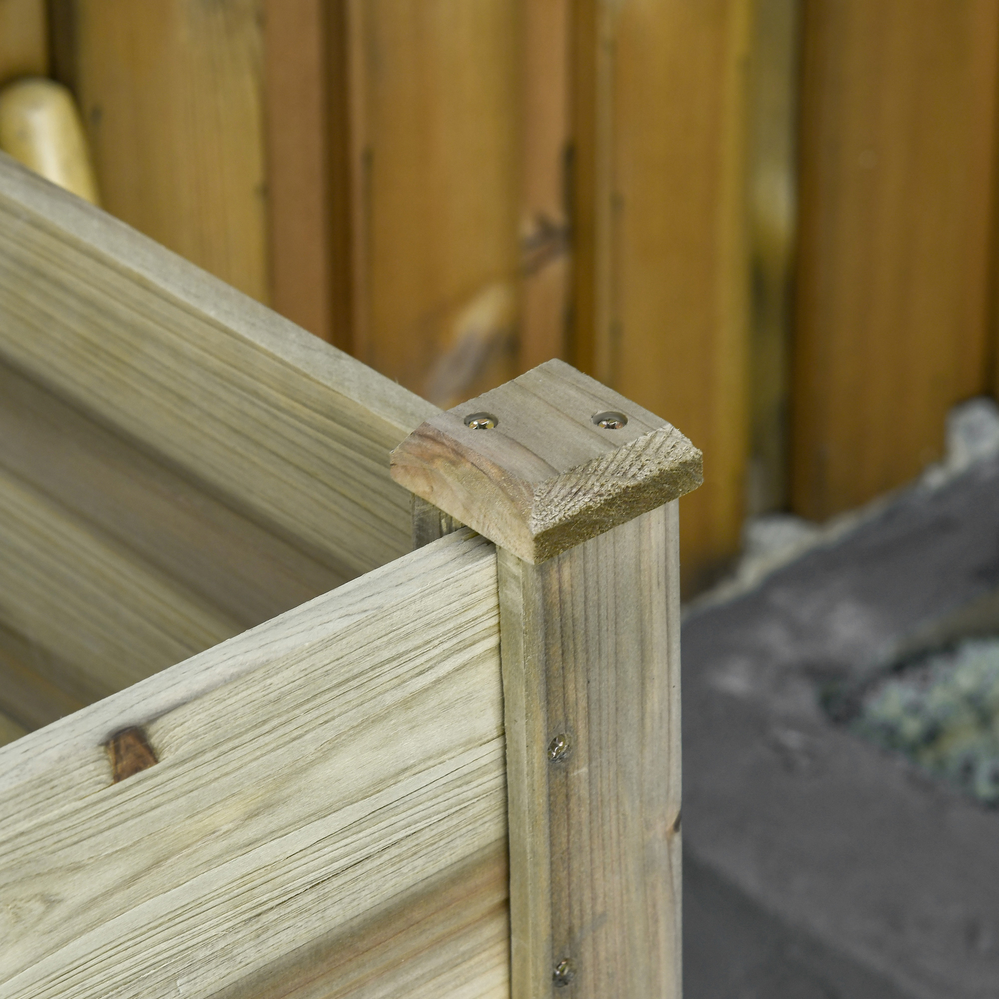 Nahaufnahme einer Ecke eines hölzernen Pflanzkastens, die Schrauben und die natürliche Holzmaserung zeigt.