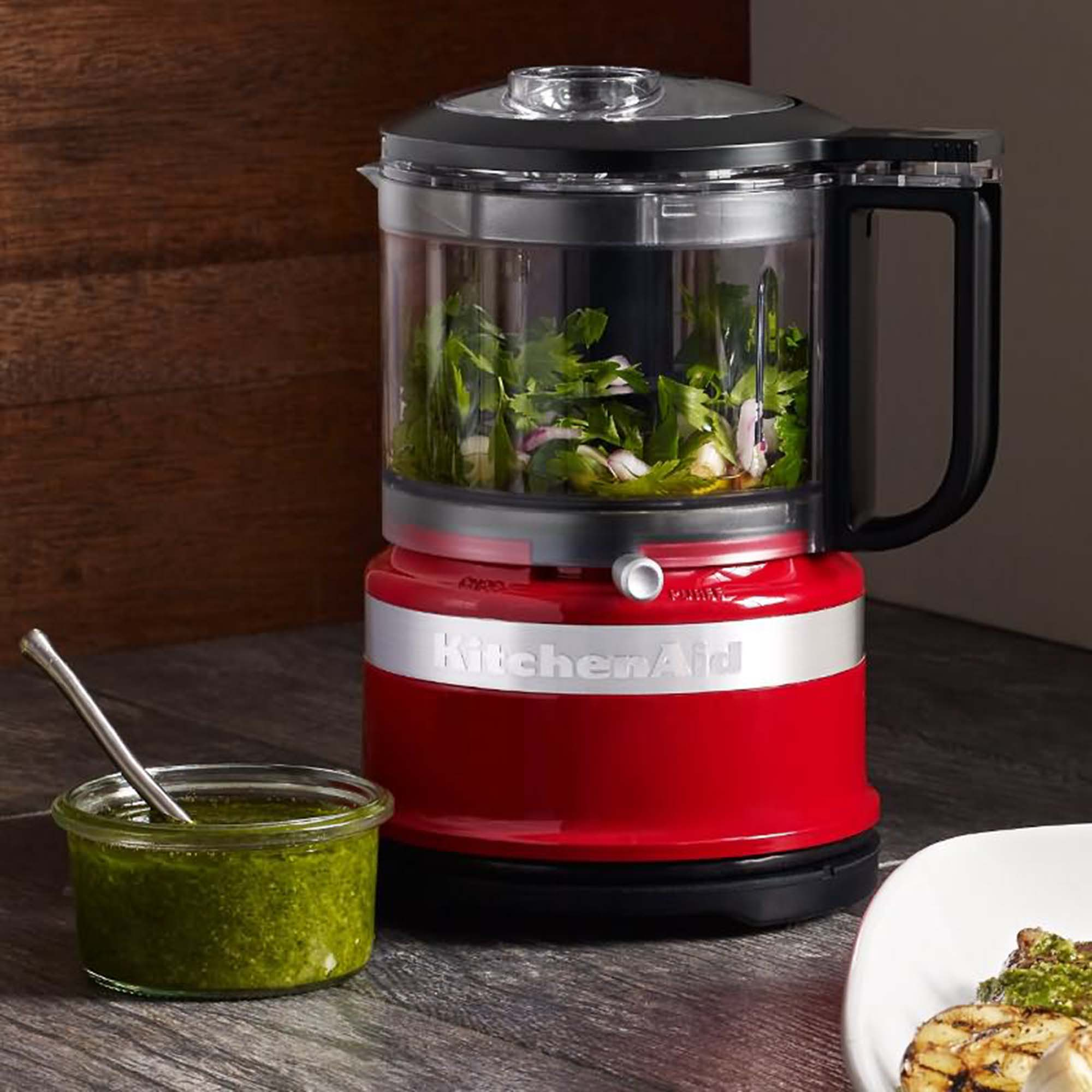 Kırmızı KitchenAid mutfak robotu, malzemeler ve küçük bir kavanoz.