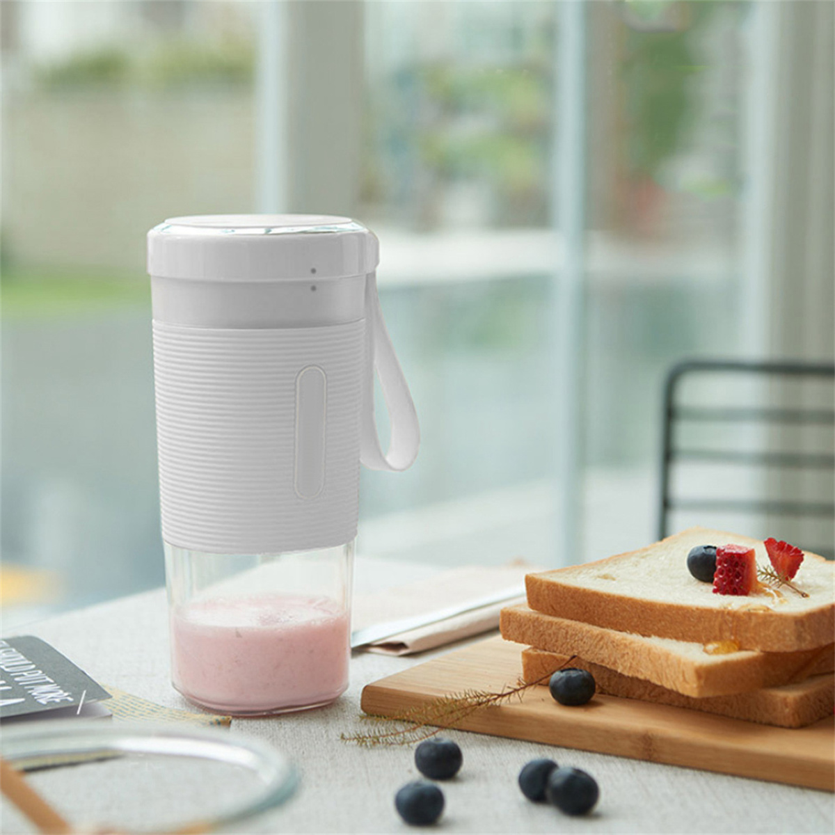 Weißer Mixer mit rosa Smoothie und Brot mit Beeren. Auf Holzbrett platziert.