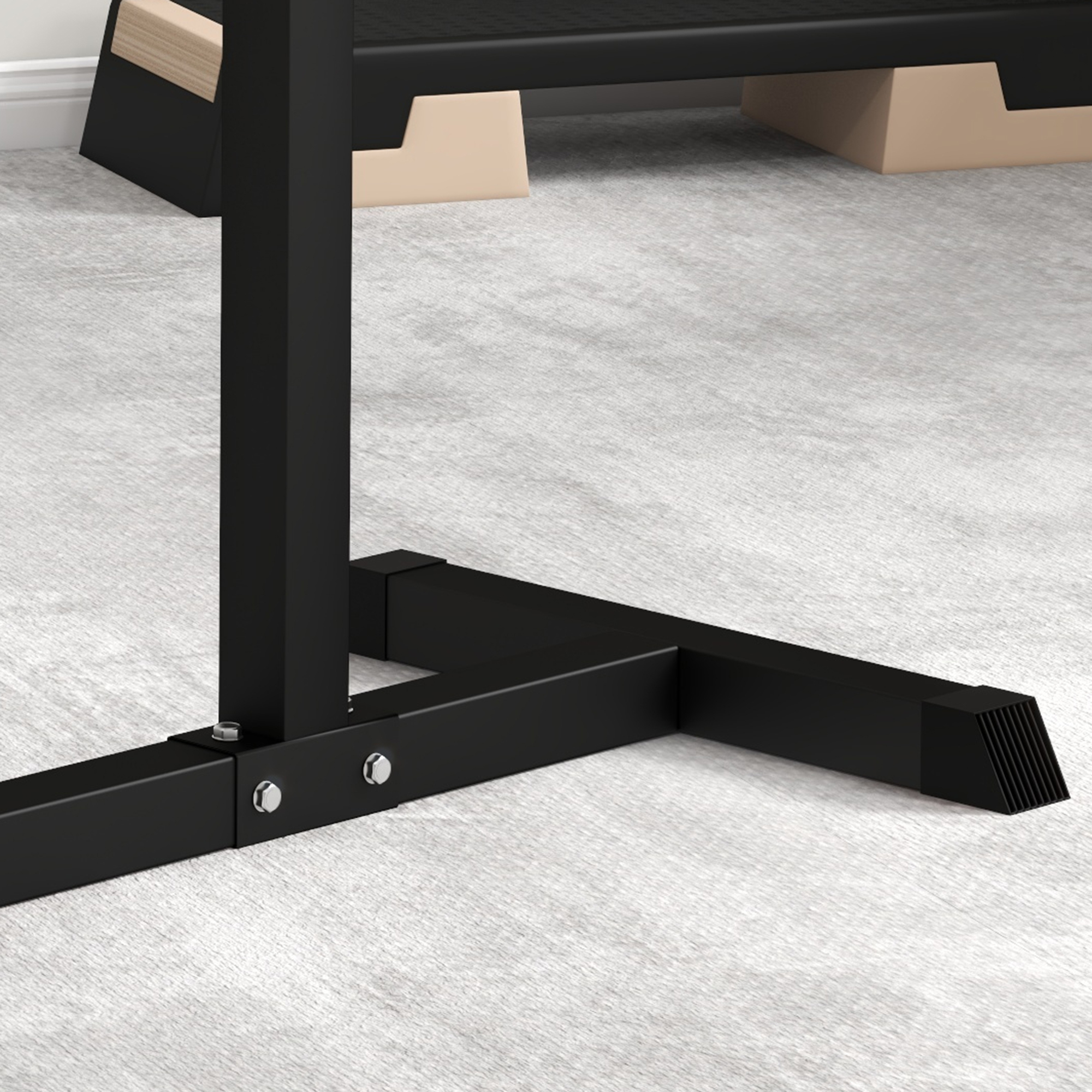 Schwarze Metallbasis für Fitnessgeräte auf hellem, grauem Teppich, mit Tritt im Hintergrund.