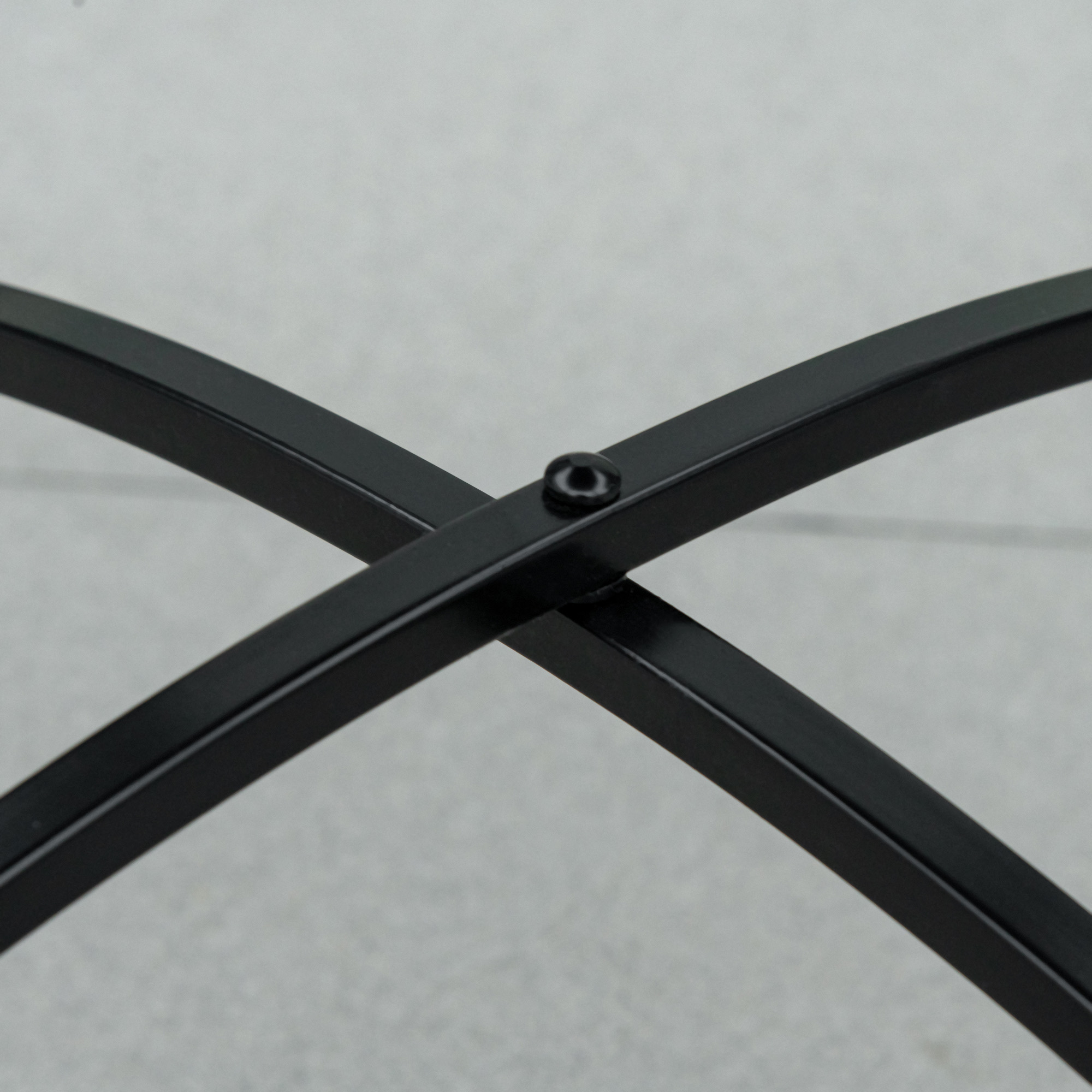 Struttura tavolo in metallo nero. Design a forma di croce. Sfondo grigio.