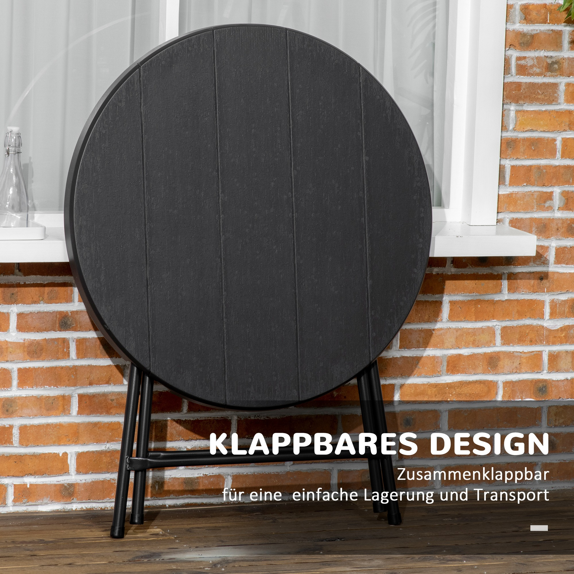 Schwarzer Klapptisch, geschlossen. Ziegelmauer im Hintergrund. Text: 'KLAPPBARES DESIGN'.