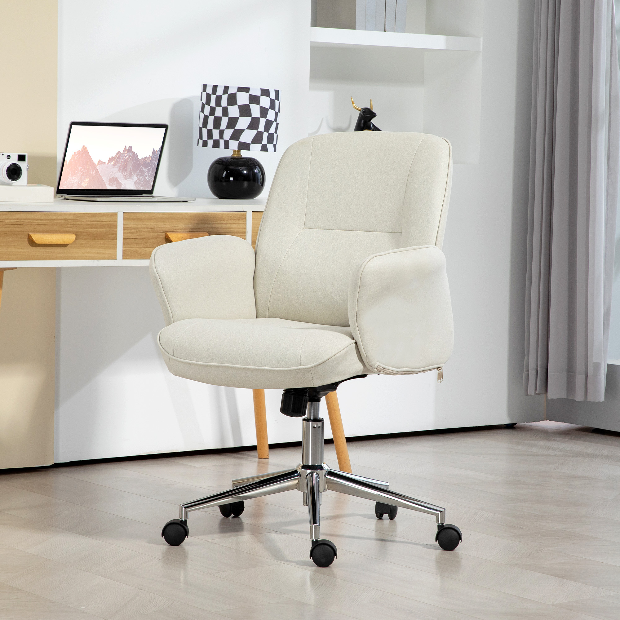 Cremefarbener Bürostuhl mit schwarzen Rädern. Schreibtisch mit Laptop, Lampe und Regal im Hintergrund.