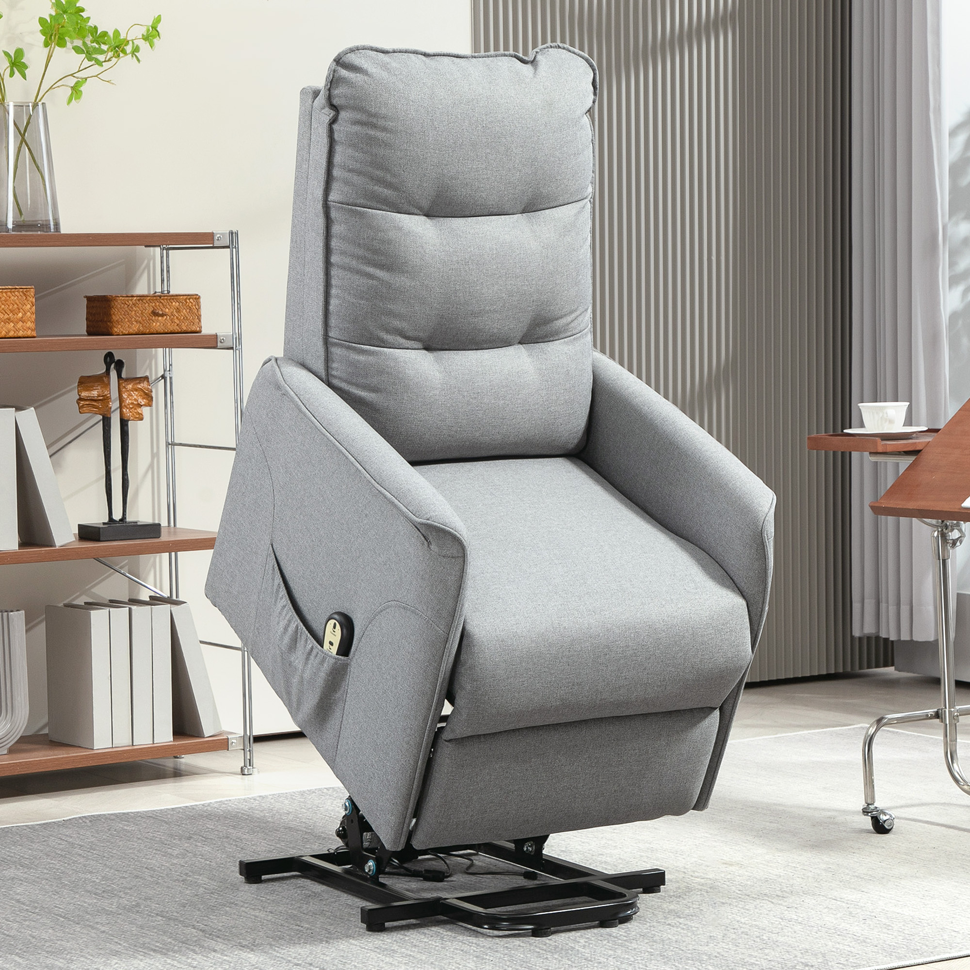 Grauer Relaxsessel mit Fernbedienung, Seitentasche und Bedienfeld. Er steht auf einem Teppich in der Nähe eines Tisches und Regals.