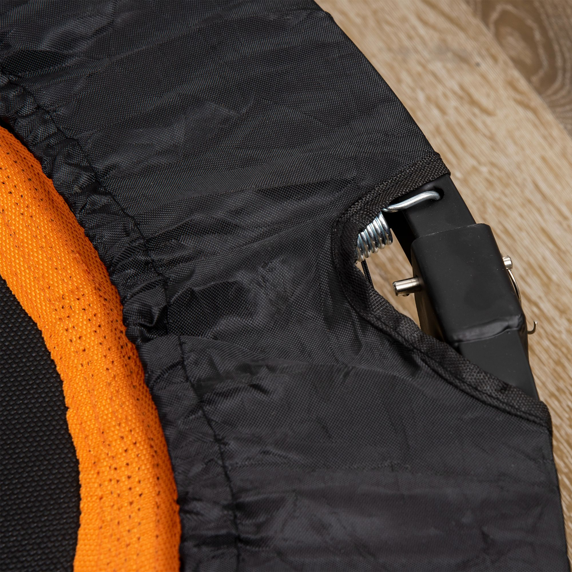 Nahaufnahme von schwarzem und orangefarbenem Mesh-Material mit einer Metallfeder und einer schwarzen Kunststoffkomponente.