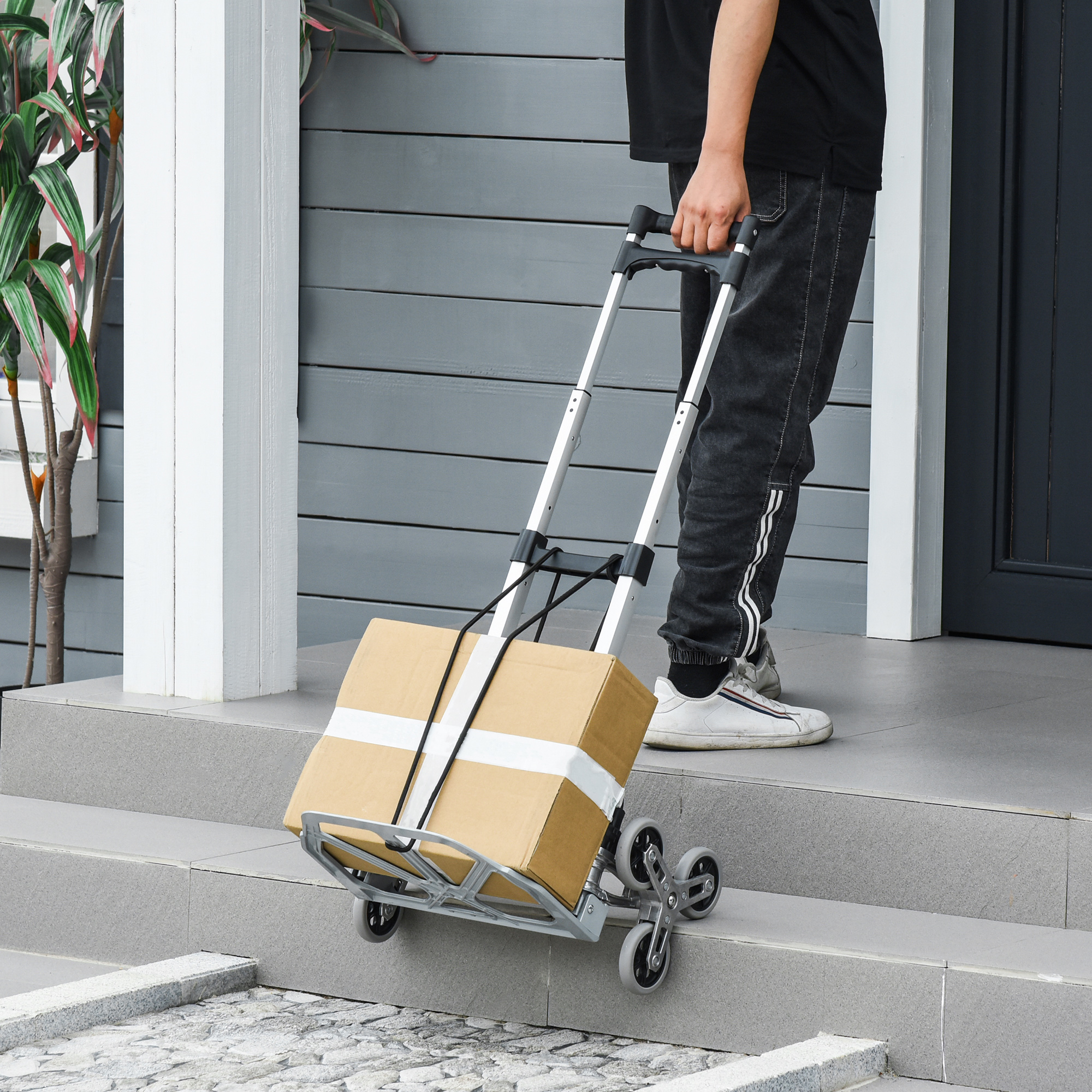 Eine Person benutzt einen Wagen mit einer Kiste, um Treppen hinunterzugehen. Der Wagen hat sechs Räder.