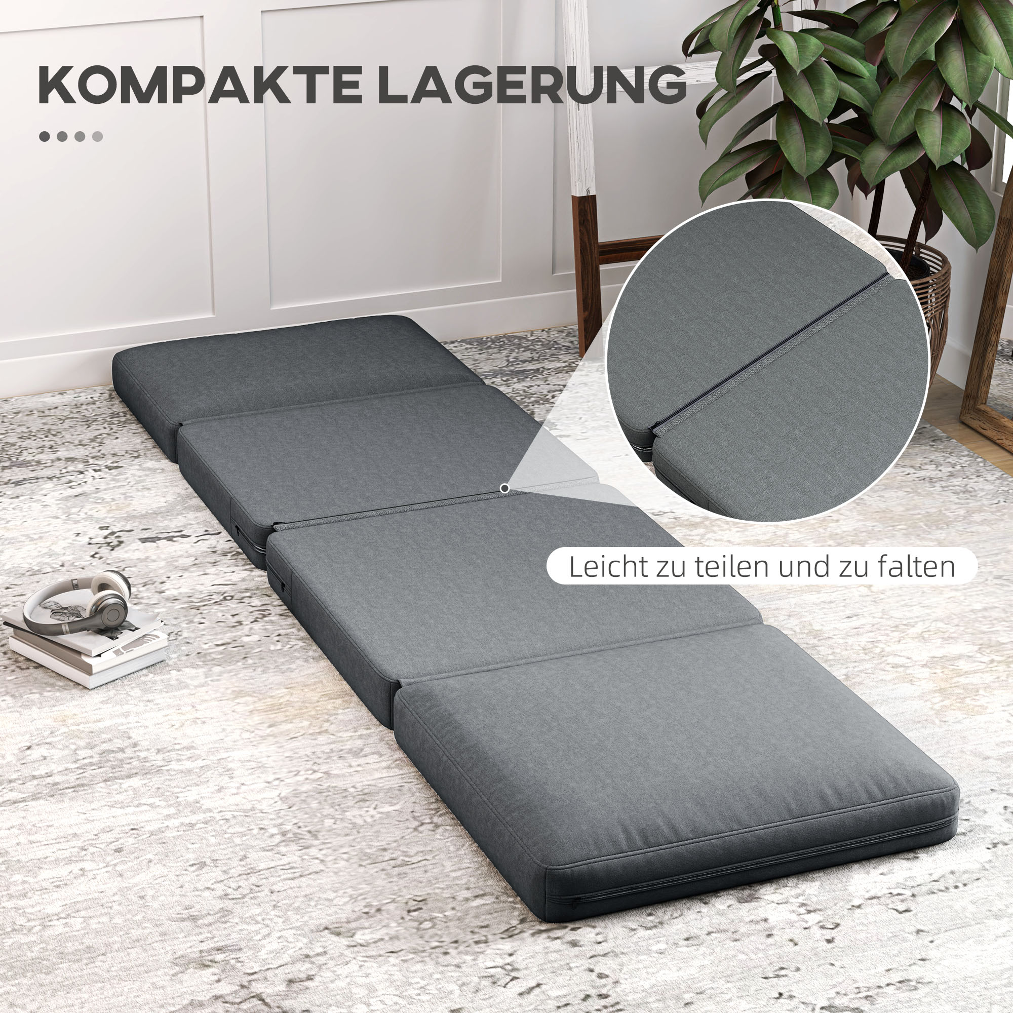 Eine graue, faltbare Matratze wird gezeigt, mit Nahaufnahme-Detail. Ein Kopfhörer liegt daneben auf einem Teppich.