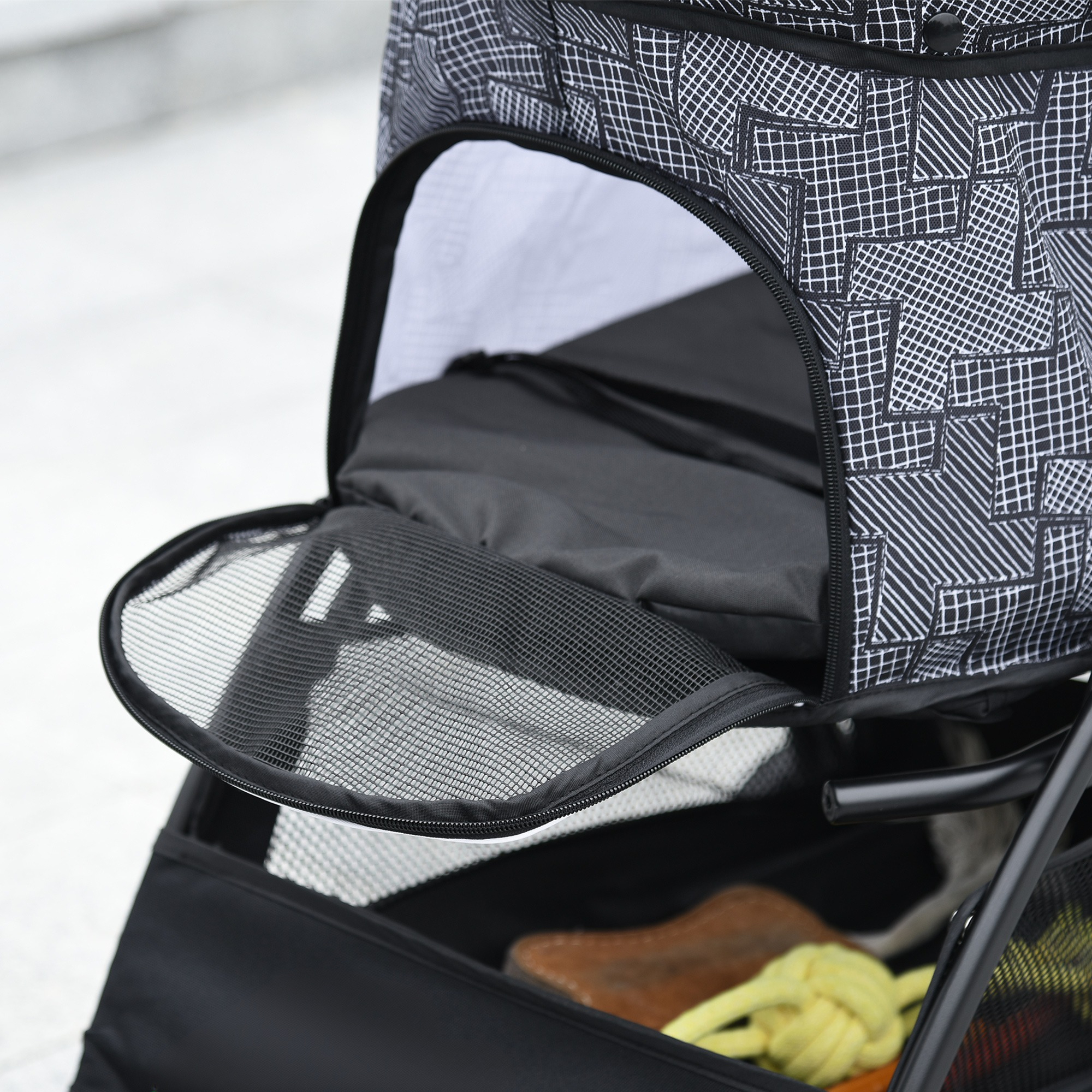 Nahaufnahme eines Kinderwagens mit Netzeöffnung. Ein gelbes Spielzeug und andere Gegenstände im Korb.
