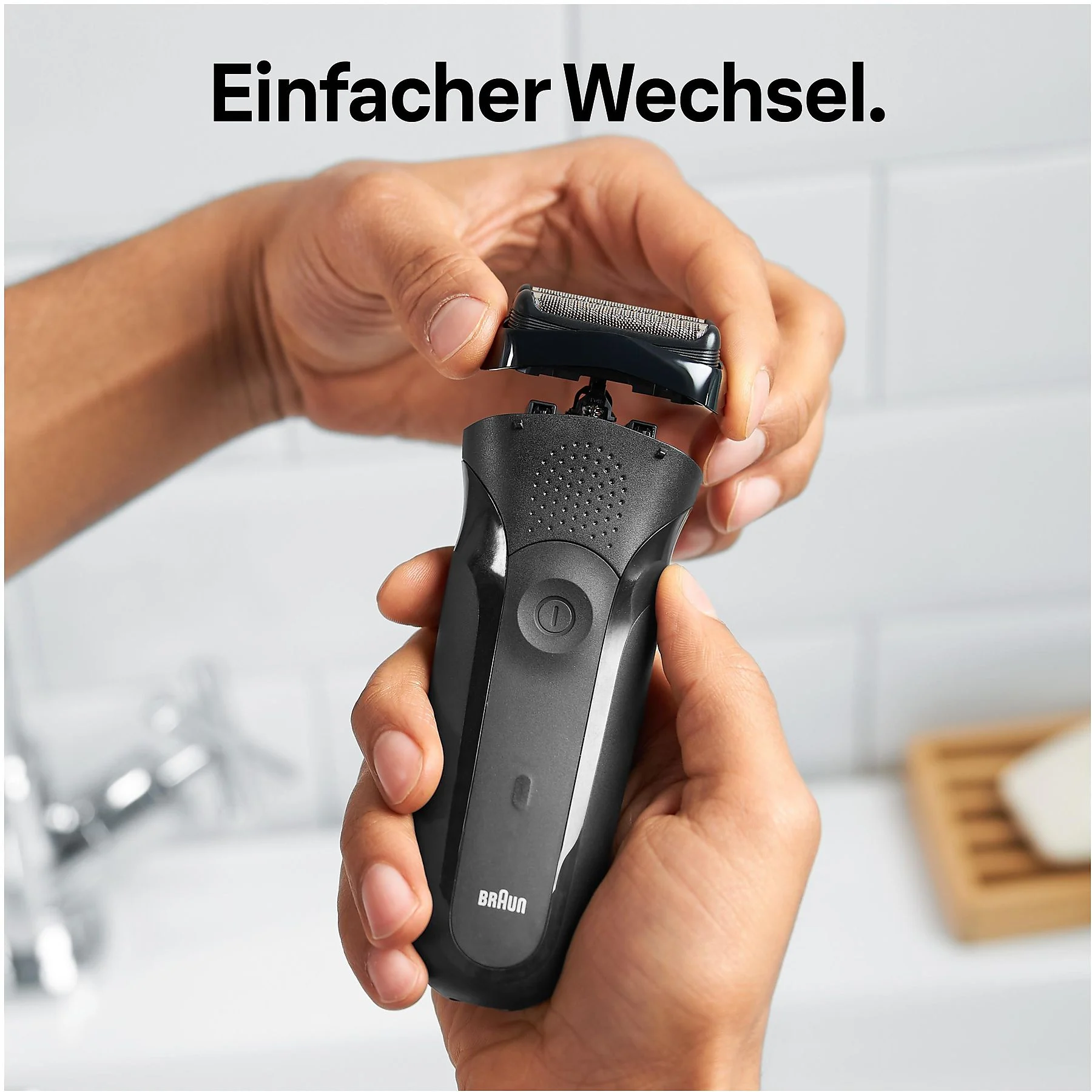 Hände halten einen schwarzen Rasierer. Der Kopf wird entfernt. Text: Einfacher Wechsel. Badezimmerhintergrund.