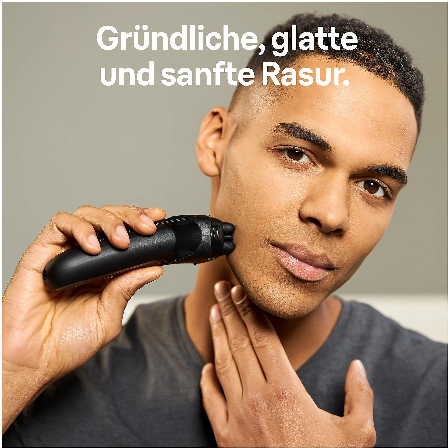 Mann rasiert sich mit einem schwarzen elektrischen Rasierer, Text auf Deutsch oben.