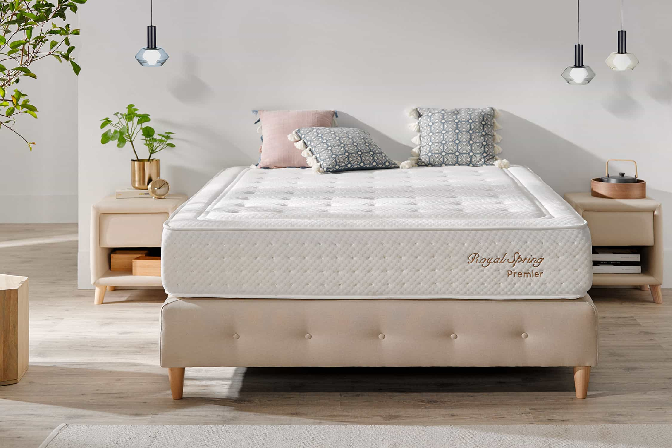 Una cama con colchón, almohadas y elementos decorativos, sobre un fondo de tonos neutros.