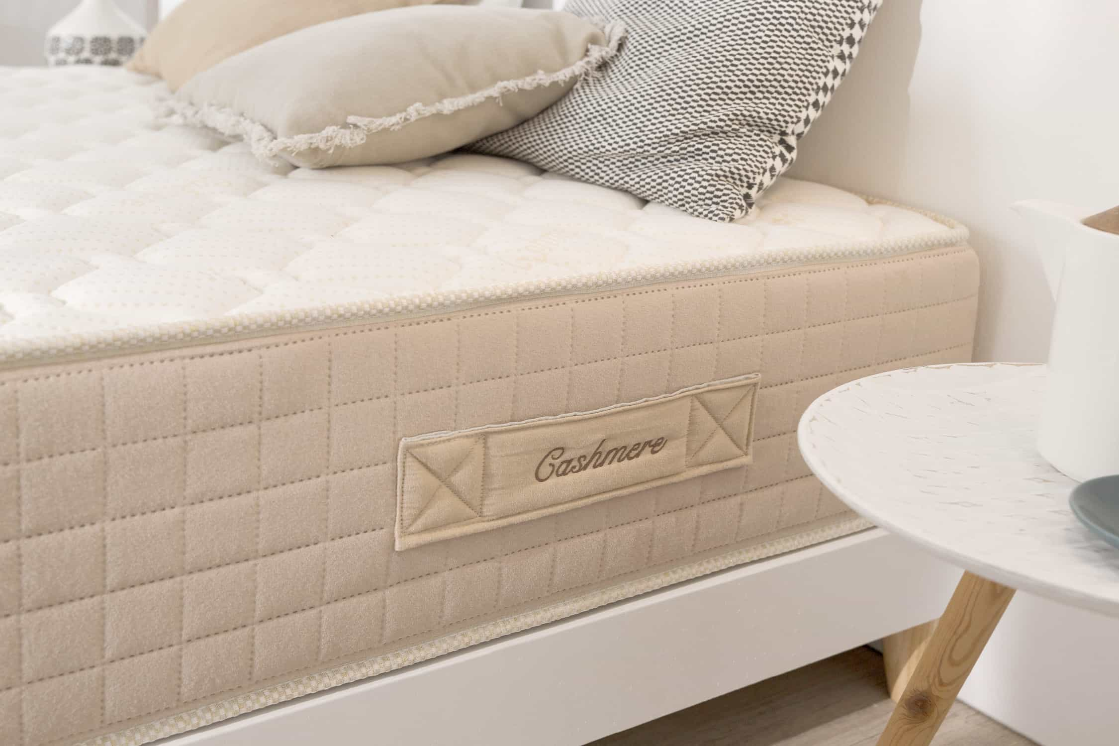 Primer plano de un colchón beige con superficie acolchada. La etiqueta dice 'Cashmere'.