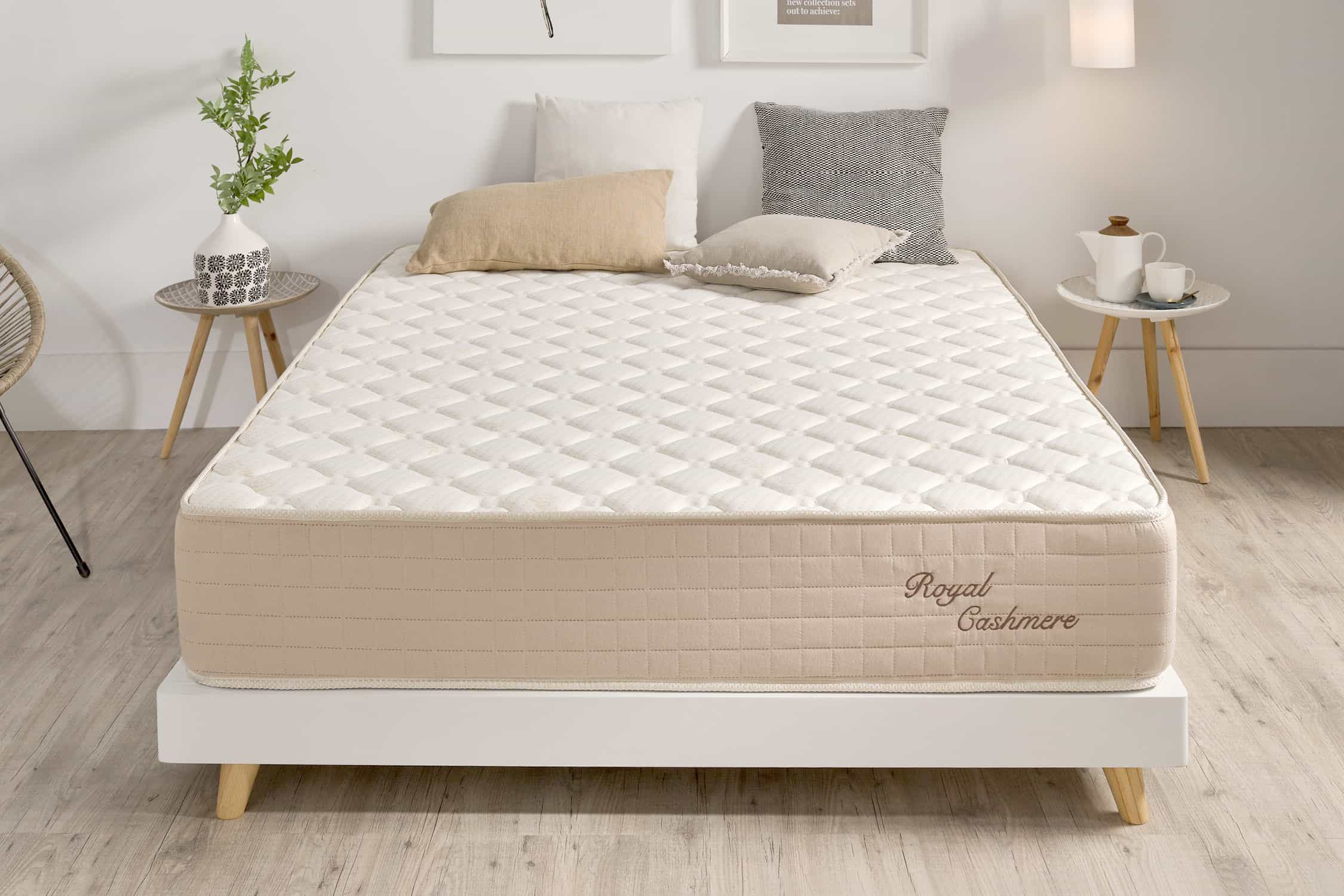 Colchón beige sobre un marco de cama blanco. La etiqueta dice 'Royal Cashmere'.